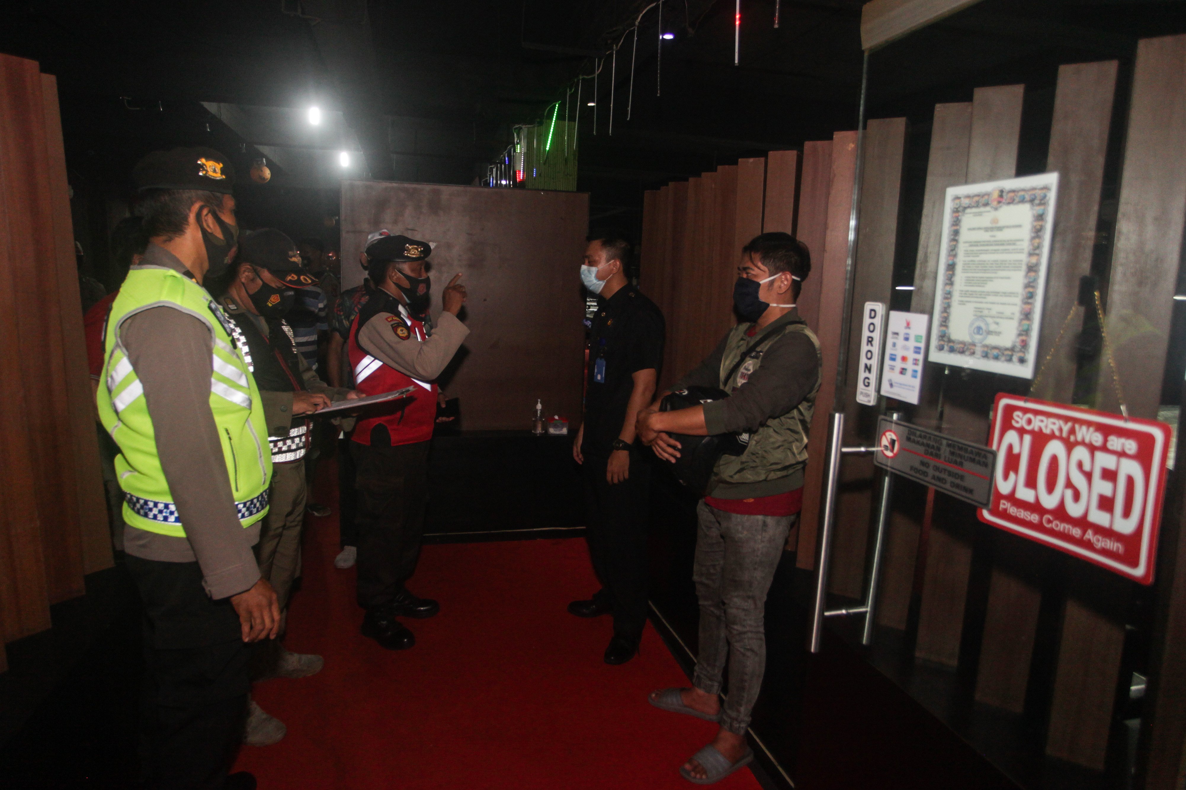 Petugas gabungan menegur penjaga tempat hiburan yang melanggar jam malam saat razia di PPKM di Palangkaraya, Kalteng, Sabtu (30/1).