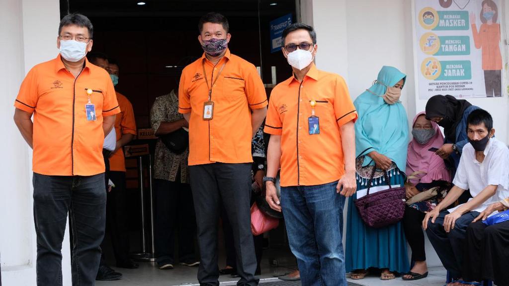 Tiga pegawai PT Pos Indonesia tengah mengawasi para penerima BST.