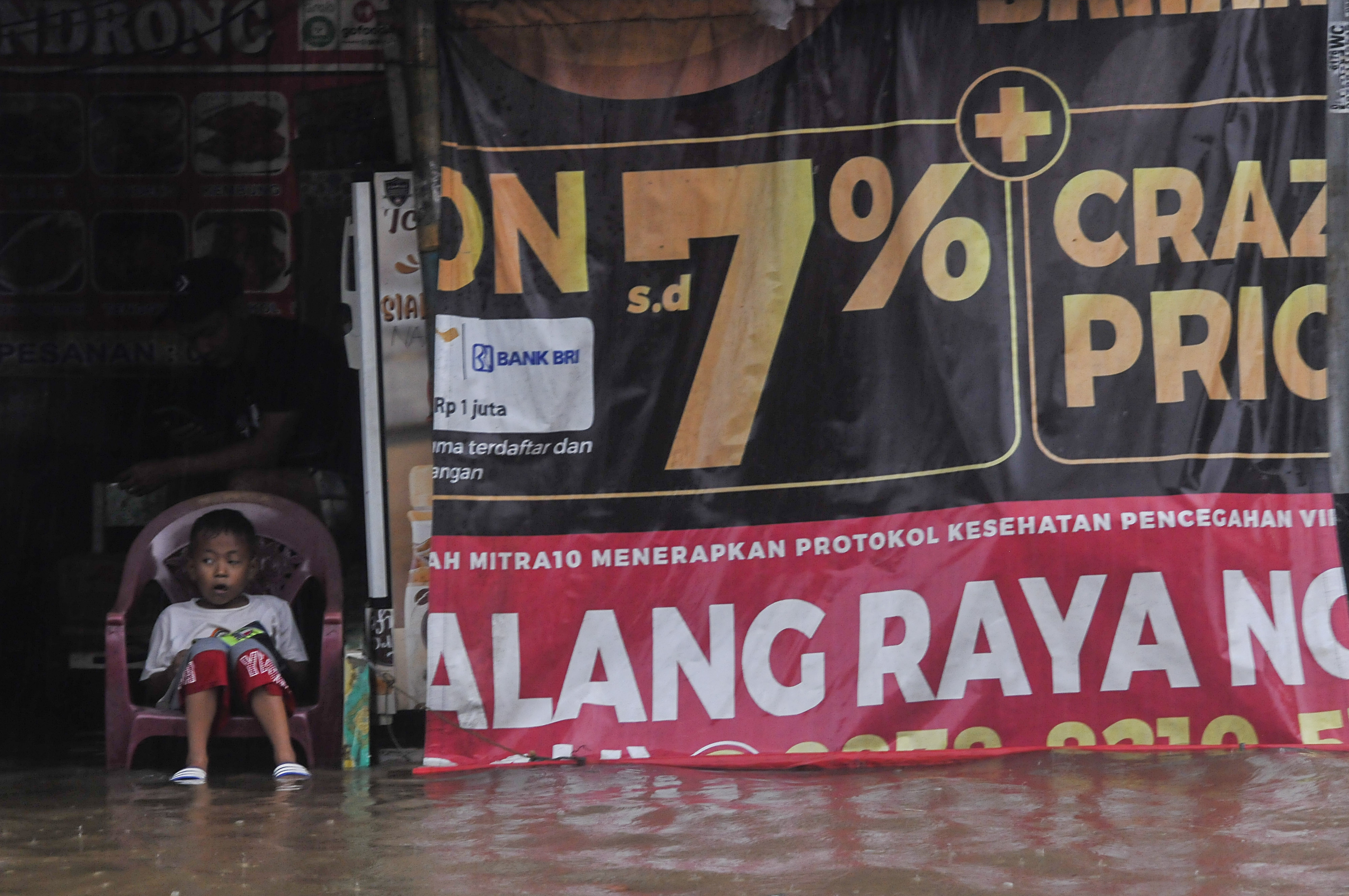 Seorang bocah beristirahat saat banjir menggenangi Jalan Caman Raya, Bekasi, Jawa Barat, hari ini.