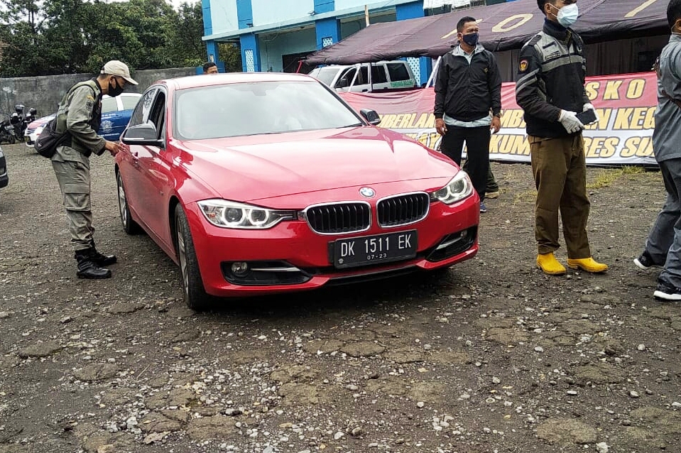 Petugas memeriksa pengendara yang hendak memasuki Kabupaten Sukabumi, Jawa Barat, di perbatasan dengan Kabupaten Cianjur, Selasa (19/1).