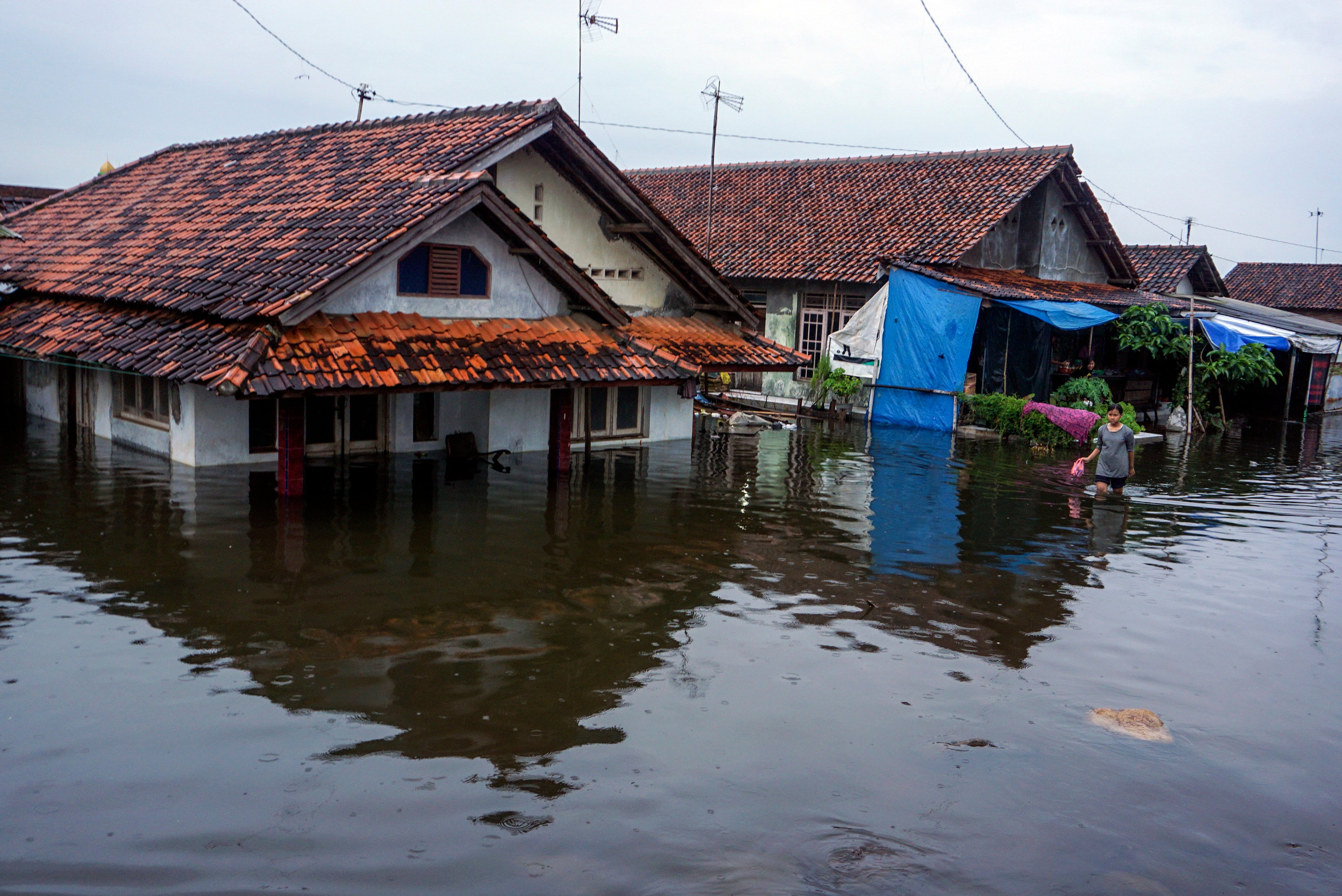 Warga berjalan di sekitar rumahnya yang tergenang banjir di Pekalongan, Jawa Tengah, Jumat (19/2/2021).