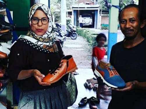 Mastangin (kanan) menunjukkan sepatu produksinya berlabel Memories bersama konsumennya.