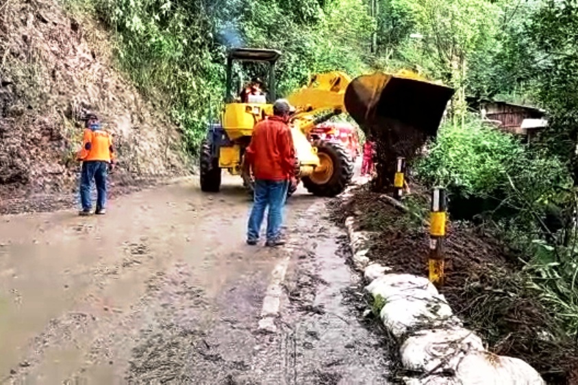 Petugas sedang membersihkan material tanah longsor yang menutup badan jalan protokol di payung tiga atau Jalan Brigjen Mohammad Manan.