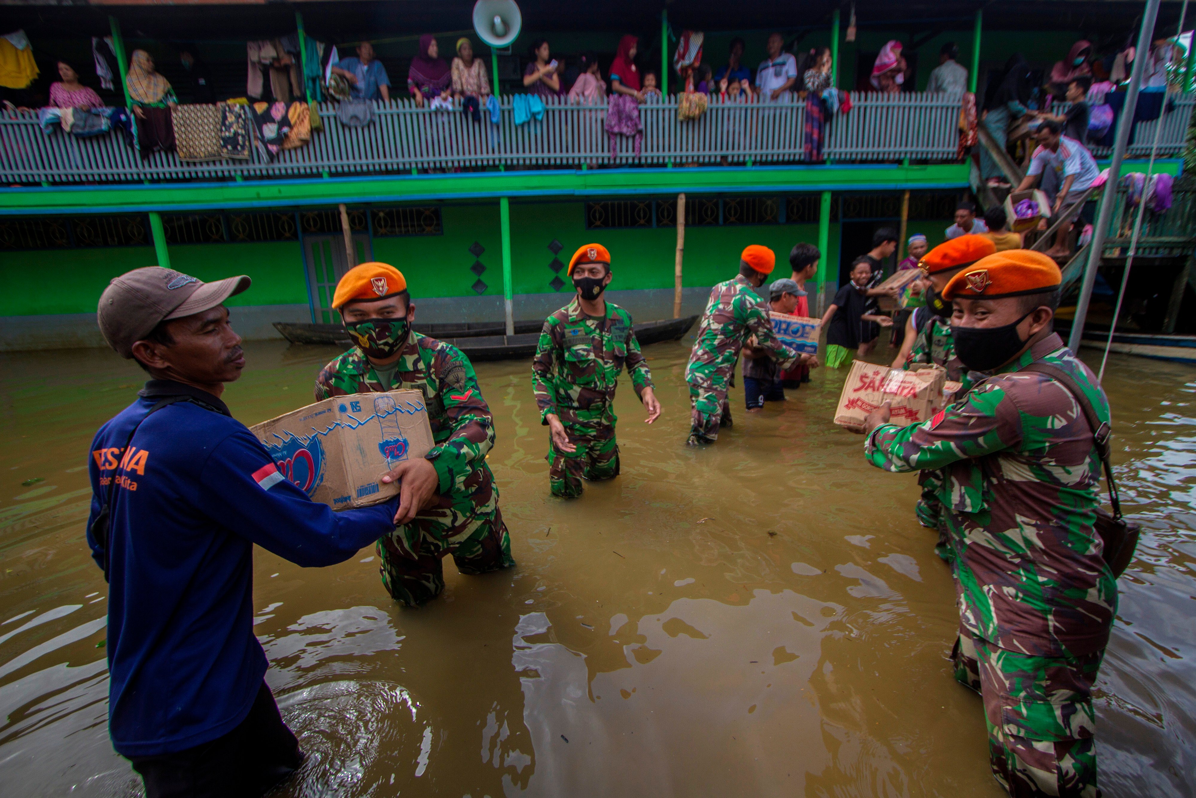 Prajurit Paskhas TNI AU bergotong royong bersama warga mendistribusikan bantuan logistik untuk warga yang terdampak banjir di Kalsel.