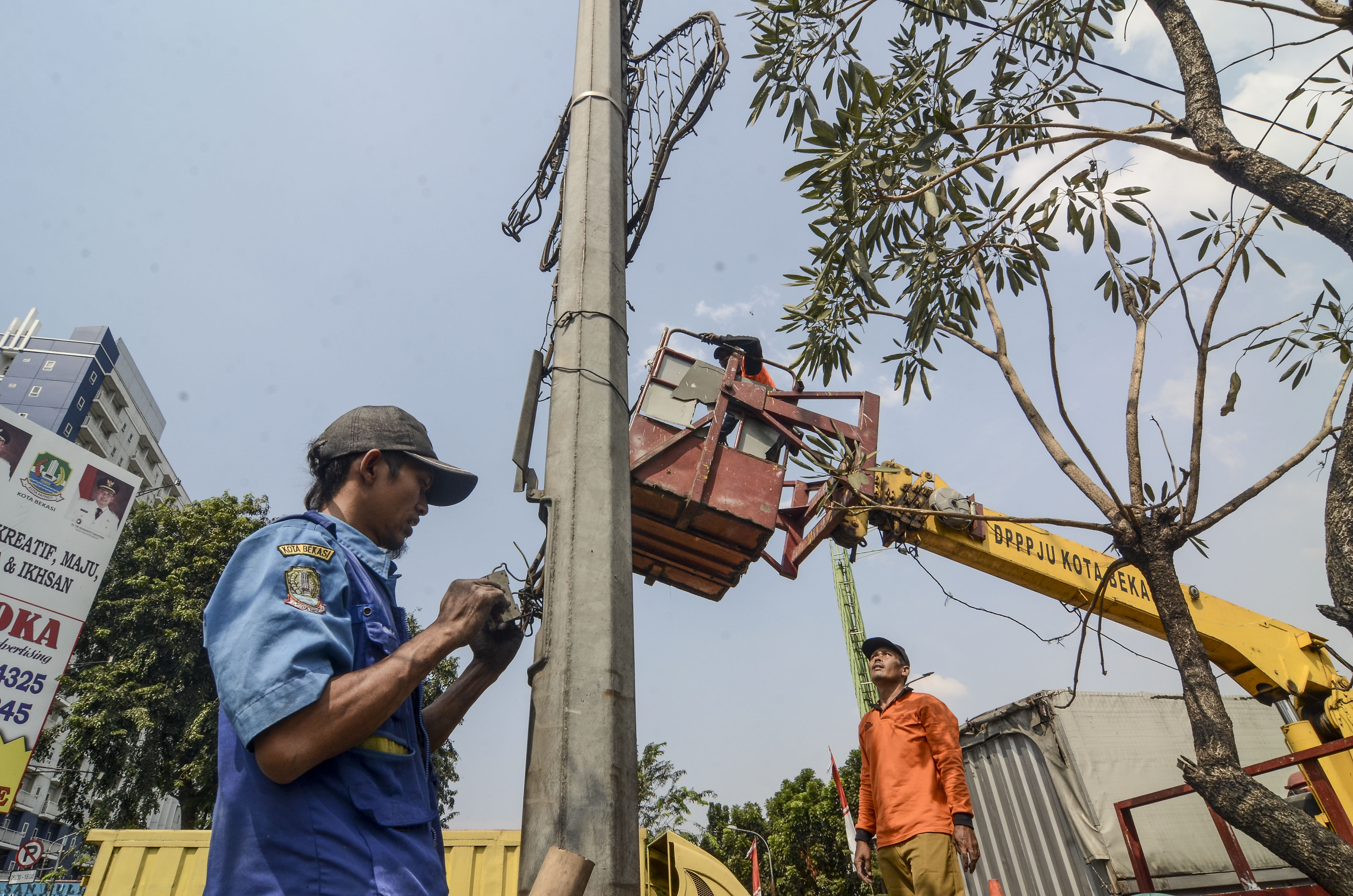 Petugas Dinas Perhubungan memperbaiku lampu penerangan jalan umum.