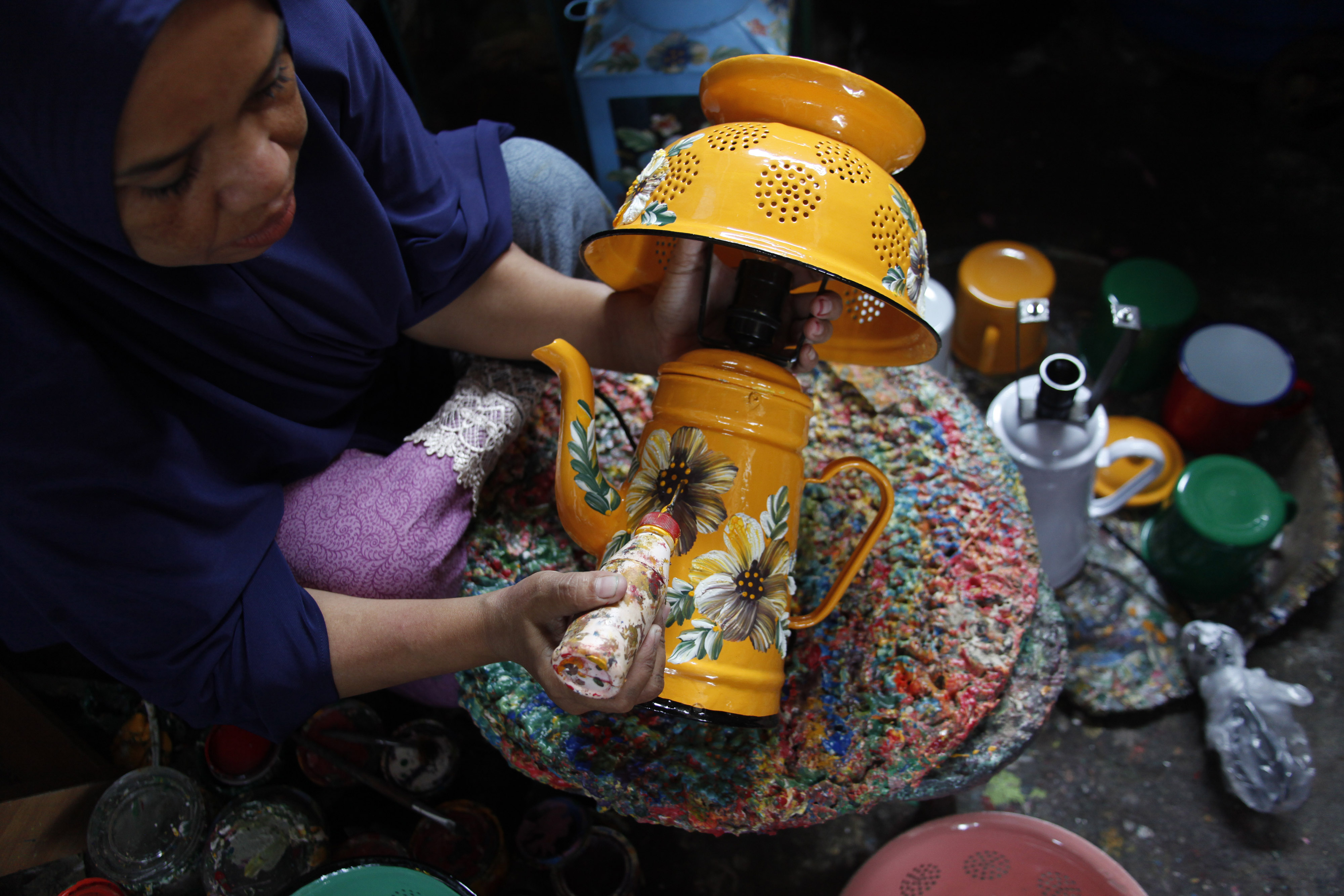 Perajin melukis lampu hias dari perabot rumah tangga daur ulang di Fairus Art Solo, Jawa Tengah, Senin (15/2/2021)
