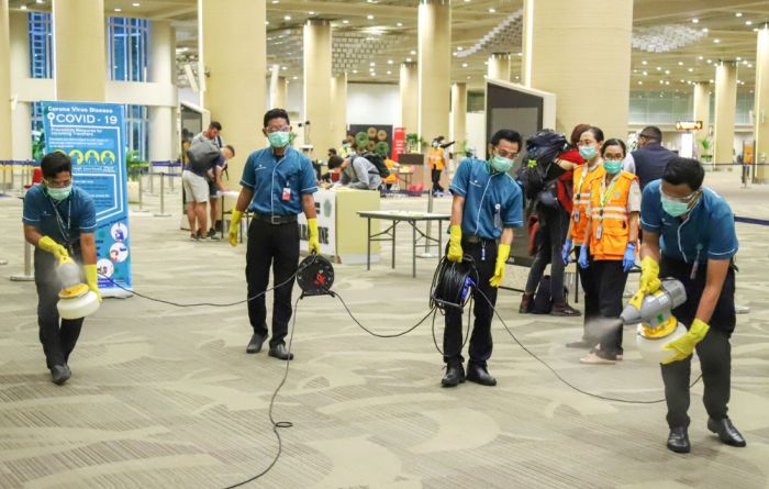 Para petugas kebersihan sednag menyemprotkan disinfektan di arela bandara Ngurah Rai.