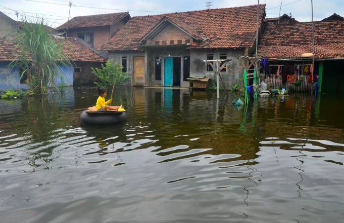 Seorang anak bermain di halaman rumah yang tergenang banjir di Dukuh Tanggulangin, Jati, Kudus, Jawa Tengah, kemarin.