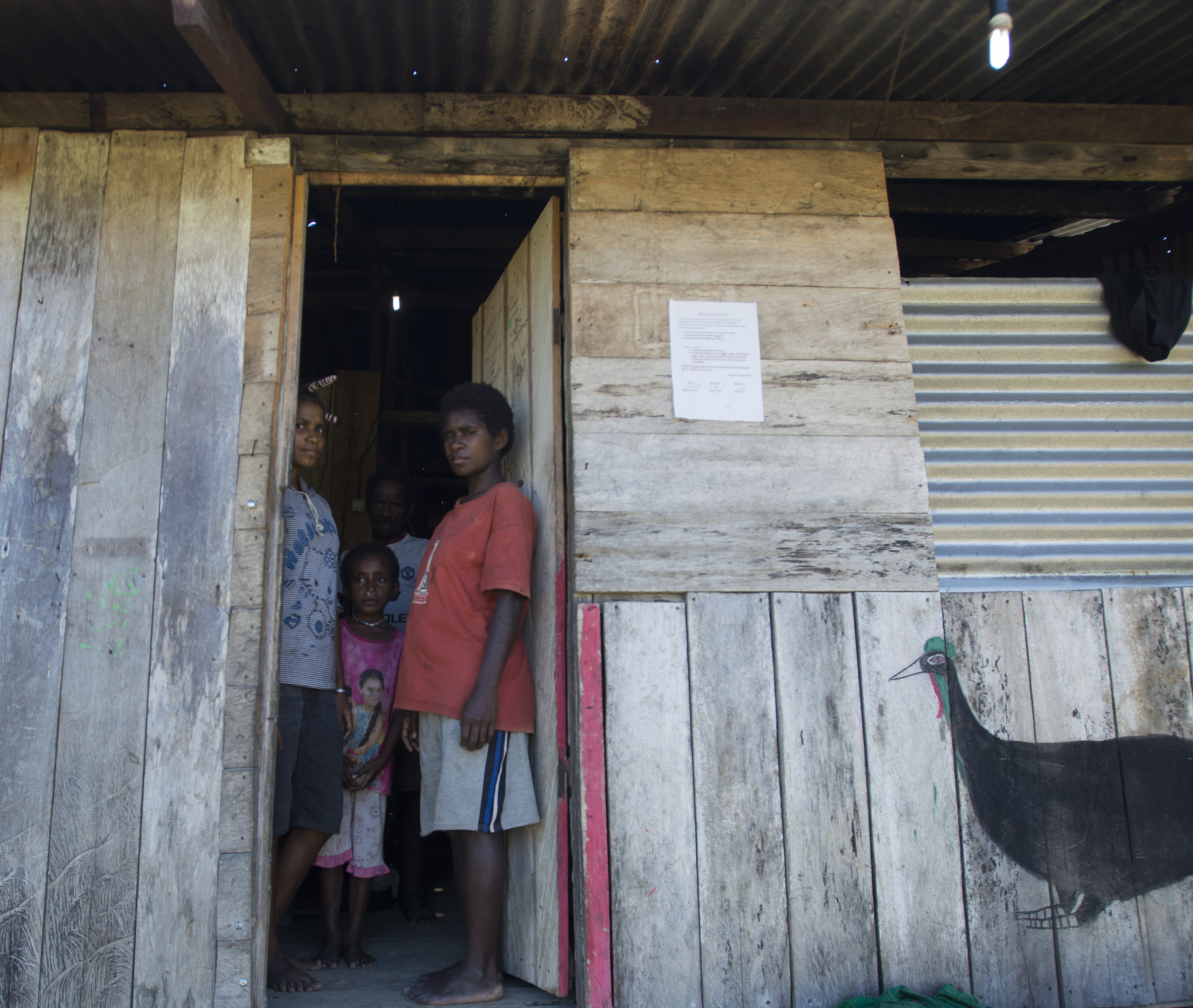 Warga Desa Sosyan berdiri di depan rumah mereka dengan lampu yang menyala 