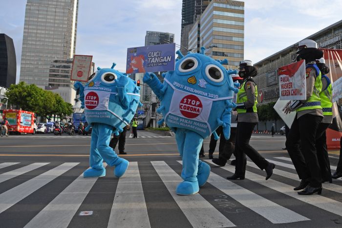 Petugas mengenakan kostum berbentuk virus korona dalam sosialisasi di kawasan Sudirman, Jakarta.  
