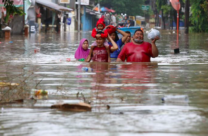 Warga menyelamatkan diri saat banjir melanda kawasan Bendungan Hilir, Jakarta.