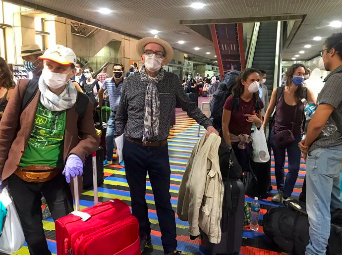 Warga asing mengenakan masker berada di bandara Caracas menunggu pesawat yang akan membawa mereka meninggalkan Venezuela.