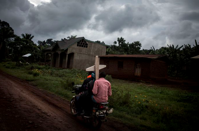 Warga mengendarai sepeda motor untuk membawa nisan kuburan bagi korban ebola. 