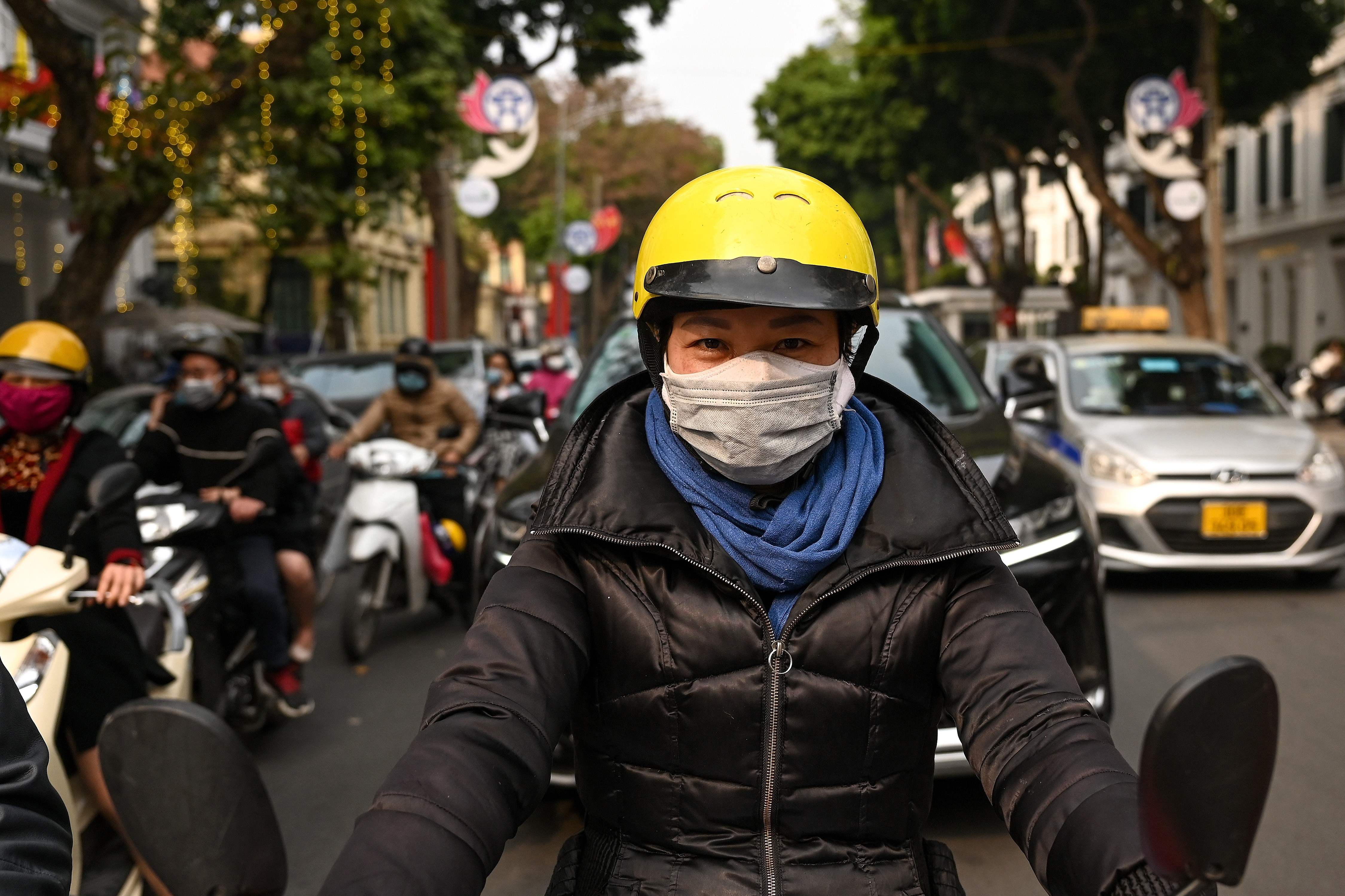 Seorang pengendara sepeda motor mengenakan masker rangkap untuk mencegah penularan virus Covid-19 di Hanoi, Vietnam. 