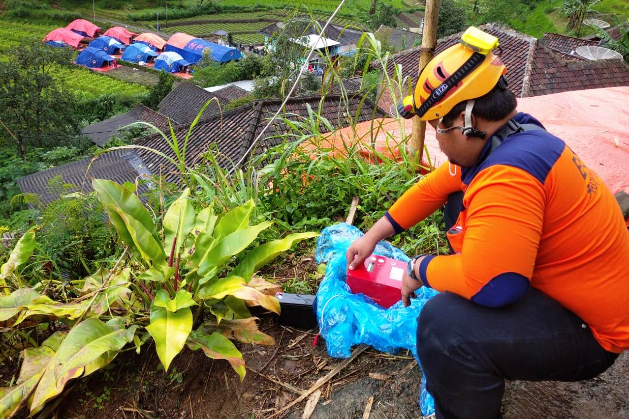 Personel Badan Penanggulangan Bencana Daerah (BPBD) Jawa Timur sedang meneliti rekahan tanah berpotensi tanah longsor.