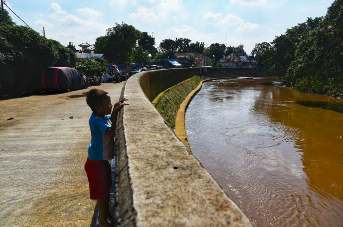 Seorang anak berdiri di bantaran Kali Ciliwung, tepatnya di wilayah Jatinegara, Jakarta Timur.