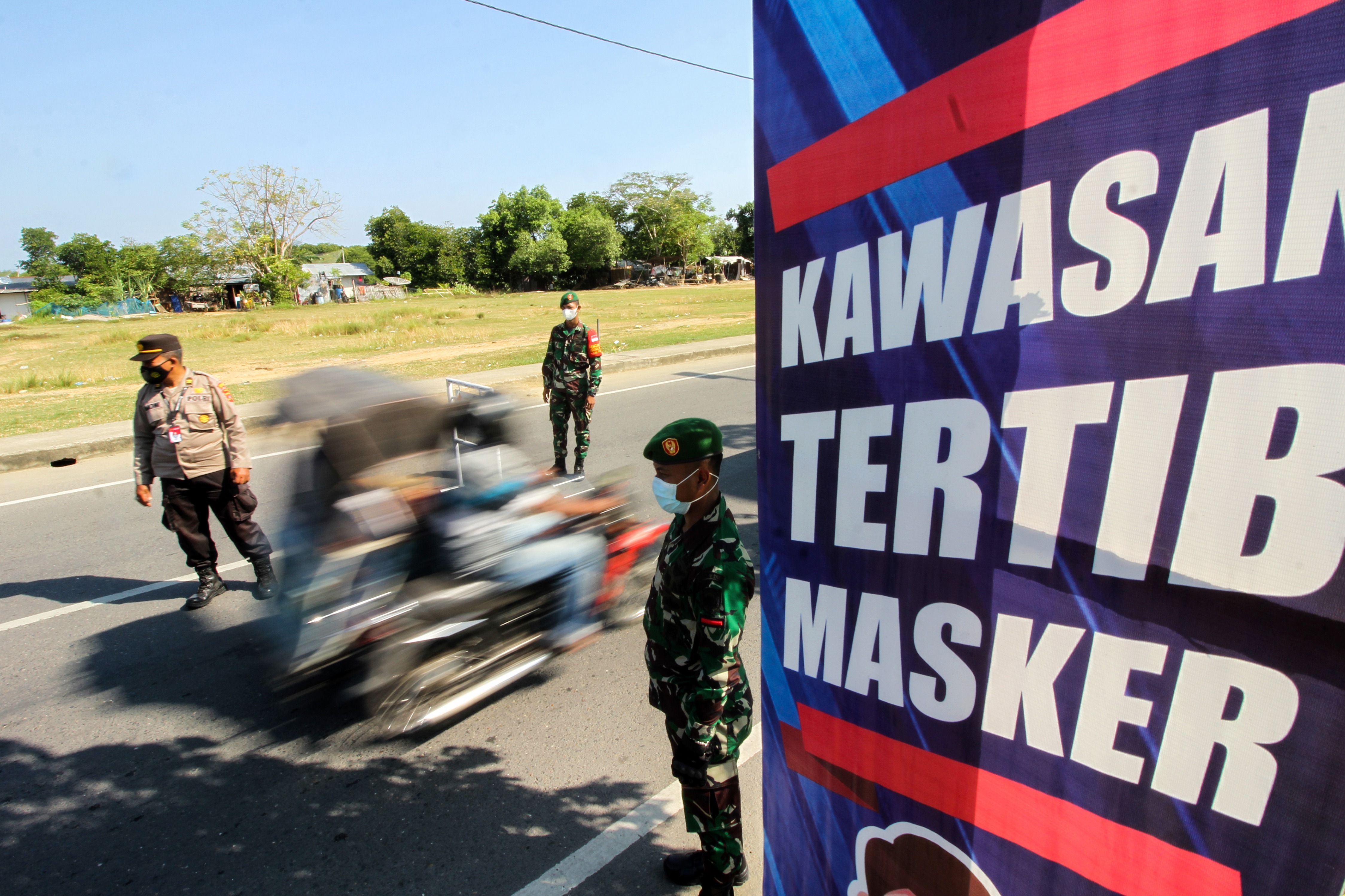 Personel gabungan mengawasi pengguna jalan raya yang tidak mengenakan masker saat razia di Lhok Seumawe, Aceh, Selasa (16/3).