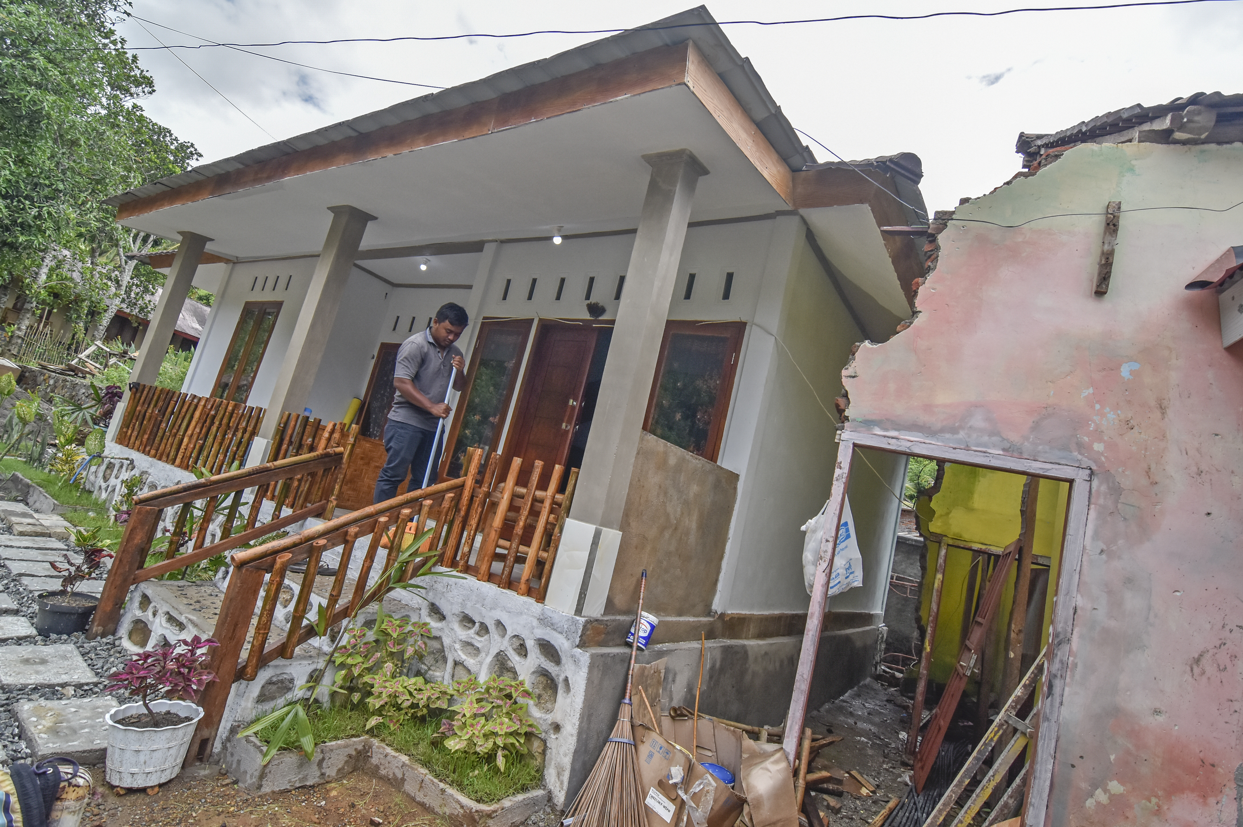 Tomi (26) menyapu teras ruang homestay yang baru selesai dibangun di rumahnya di Mandalika
