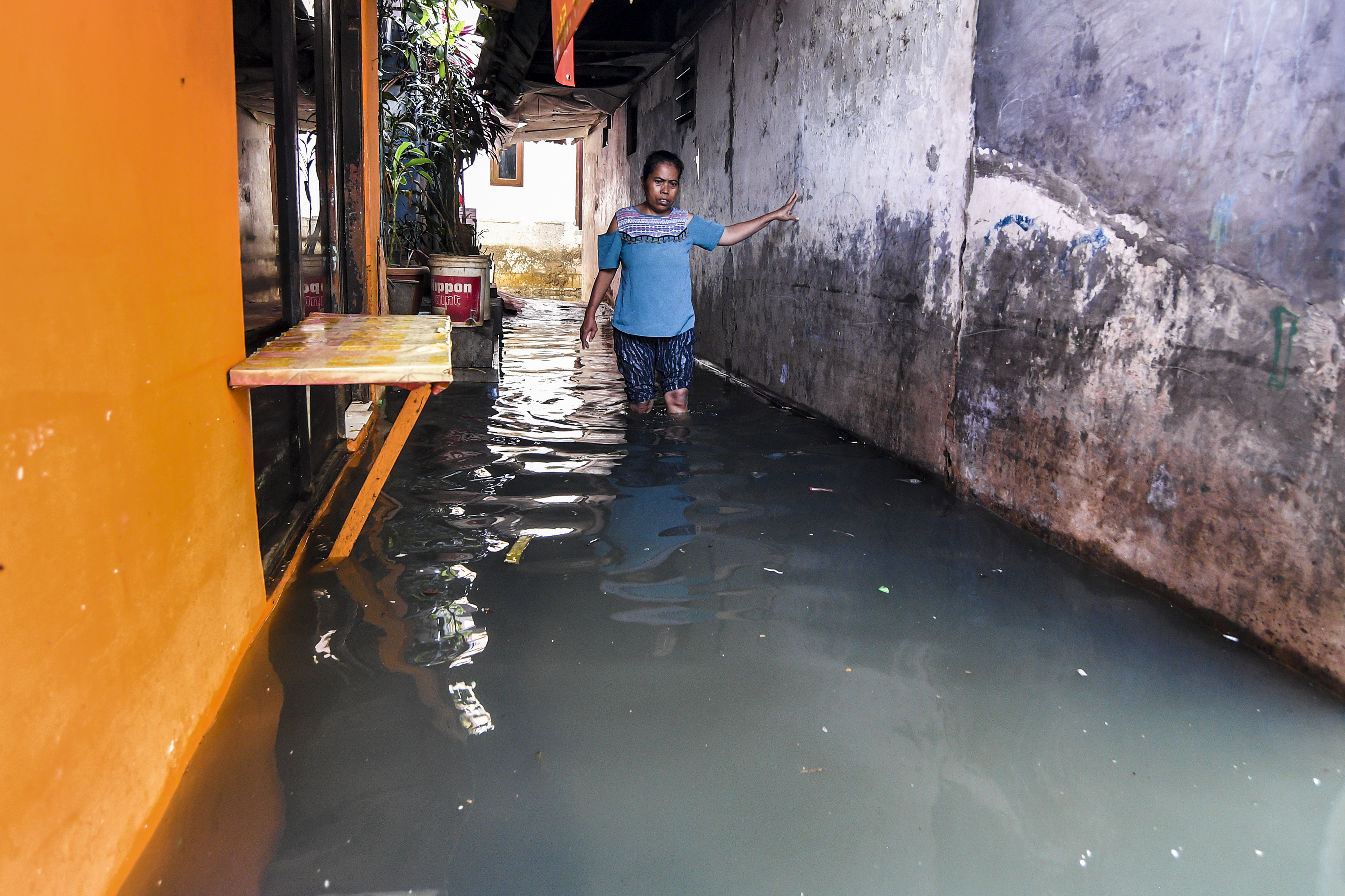 Warga berjalan melintasi banjir di kawasan Kedoya Utara, Jakarta.