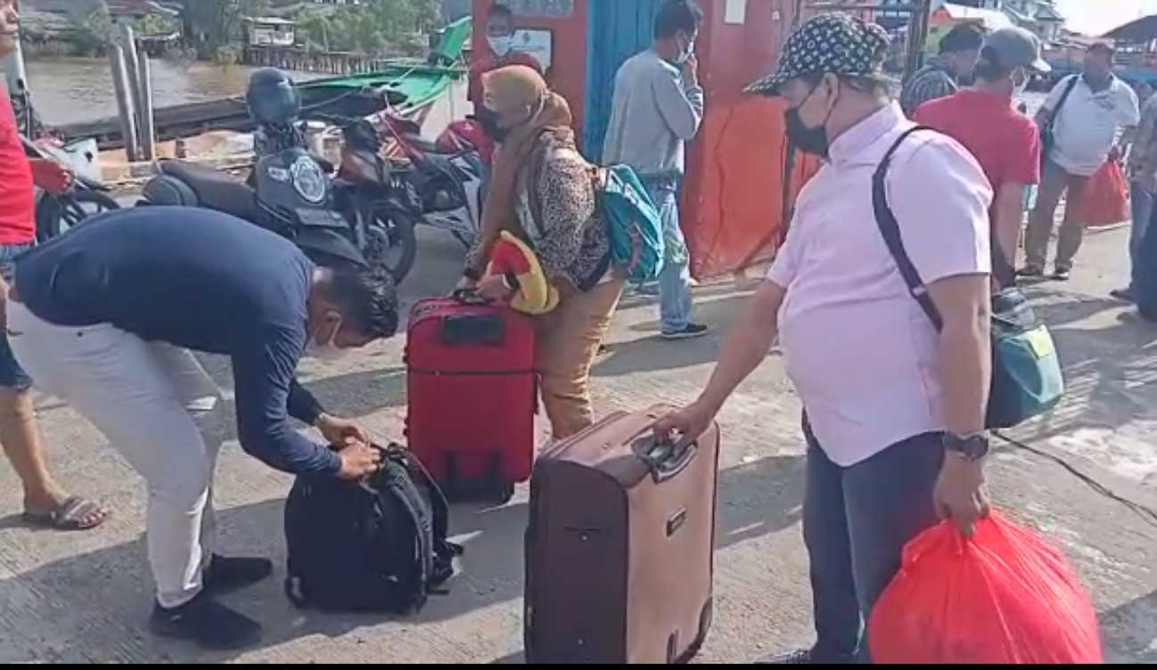 Petugas kepolisian  berbaju preman memeriksa tas penumpang yang baru turun dari pelabuhan kecil di pinggiran Kota Kuala Tungkal, Jambi.