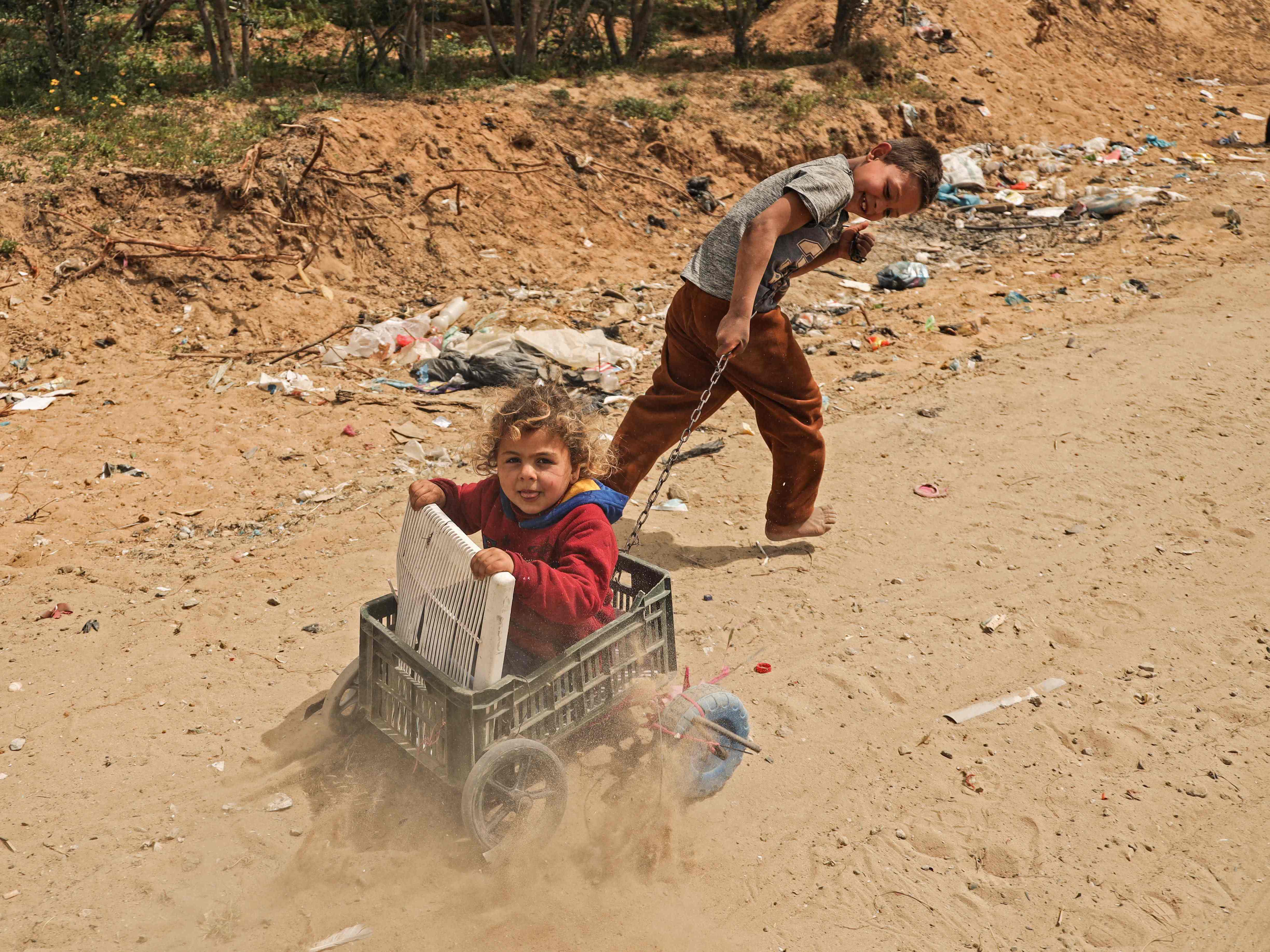 Anak-anak Palestina bermain di samping rumah mereka di Kota Gaza, Senin (22/3).