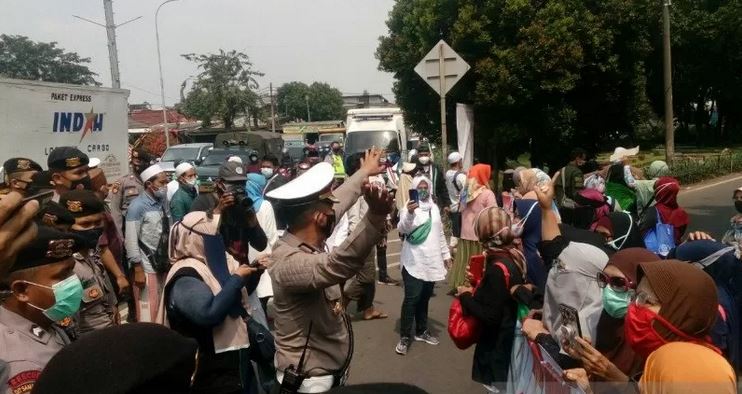 Petugas Kepolisian menghalau massa simpatisan Rizieq Shihab yang hendak berorasi di depan Pengadilan Negeri Jakarta Timur, Jumat (19/3).