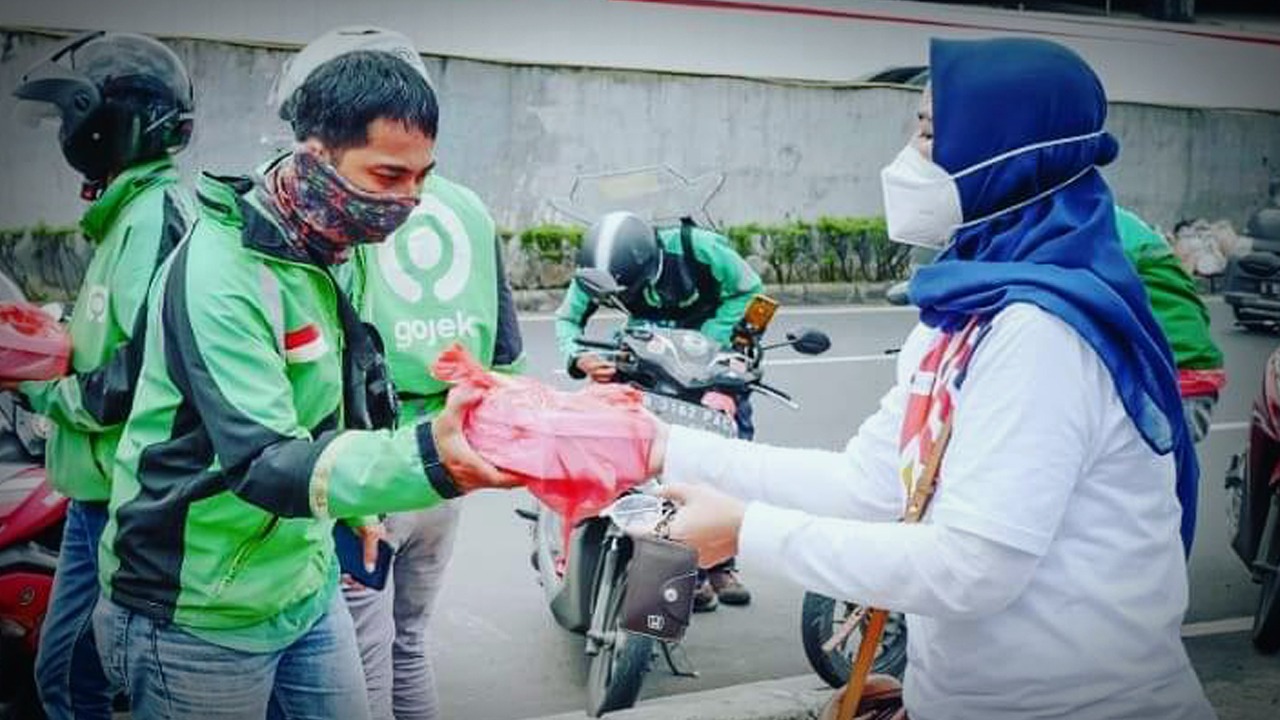 Anggota  Komunitas Insan Sukarela Indonesia membagikan nasi kotak kepada pengemudi ojol, Seni (1/3/2021).