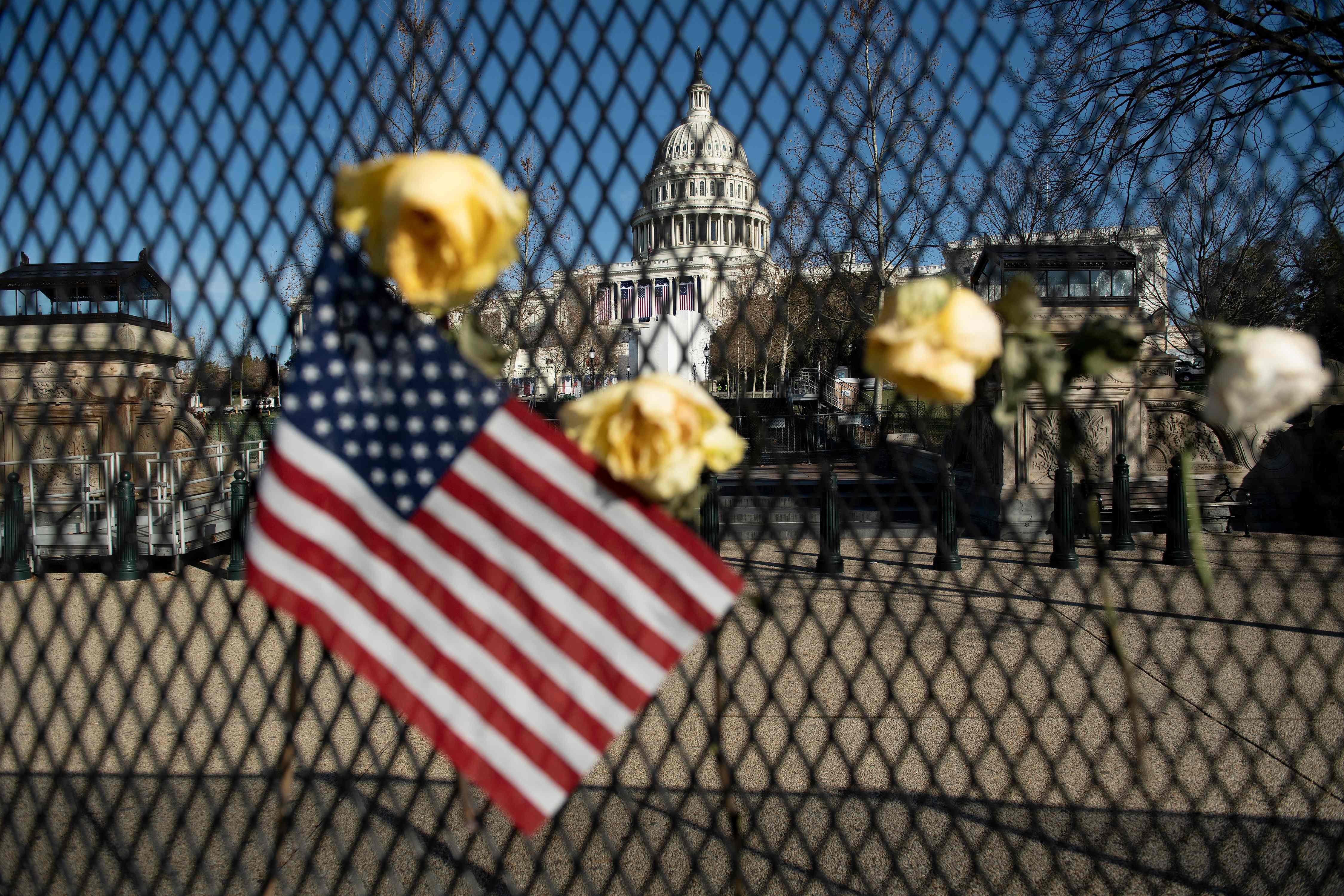 Bendera AS dan bunga dipasang di pagar pembatas Gedung Capitol, Washington DC sepekan setelah insiden penyerangan oleh pendukung Trump.