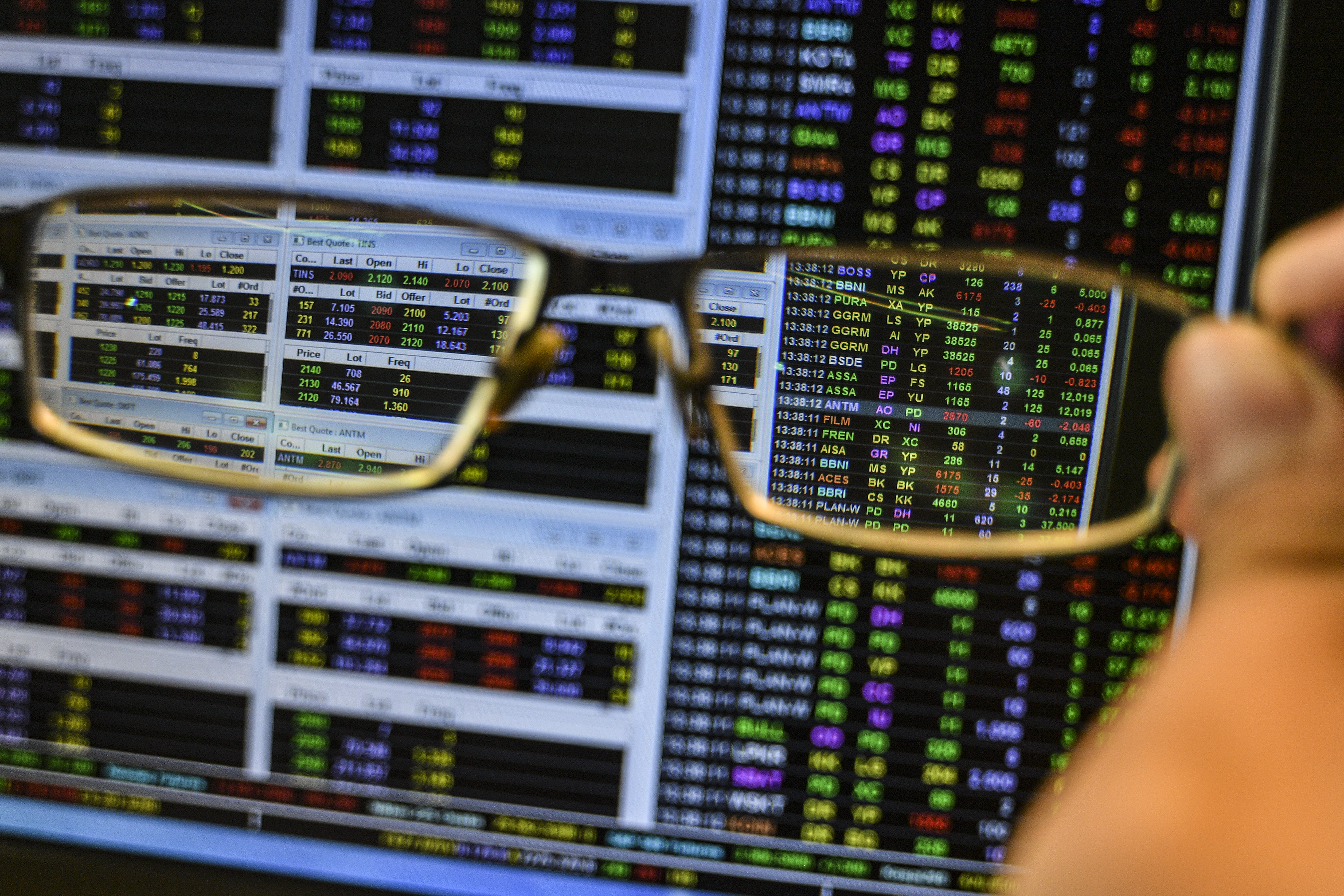 Karyawan memegang kacamata miliknya saat mengamati pergerakan harga saham di Jakarta, Kamis (11/2/2021).