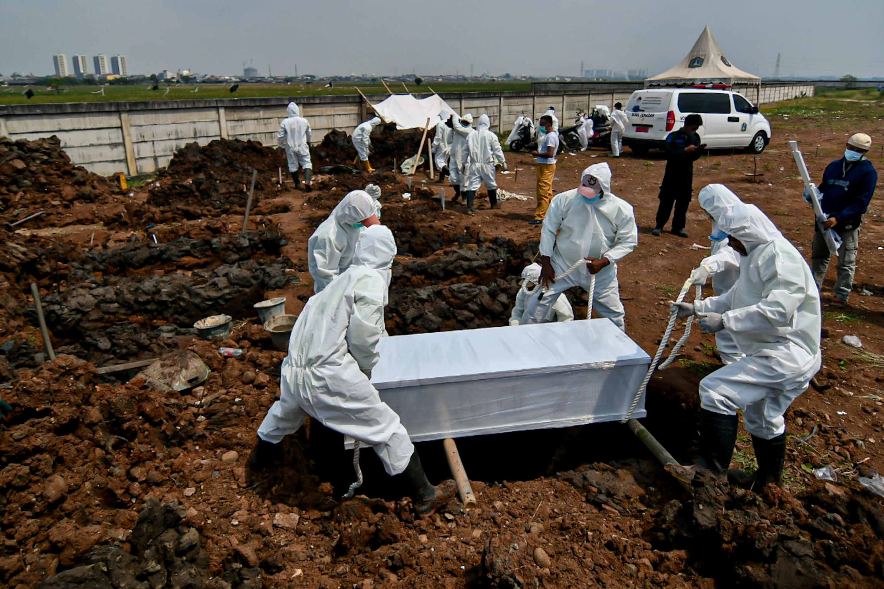 Petugas menggunakan APD saat memakamkan jenazah pasien covid-19 di Tempat Pemakaman Umum (TPU) Rorotan, Jakarta Utara.