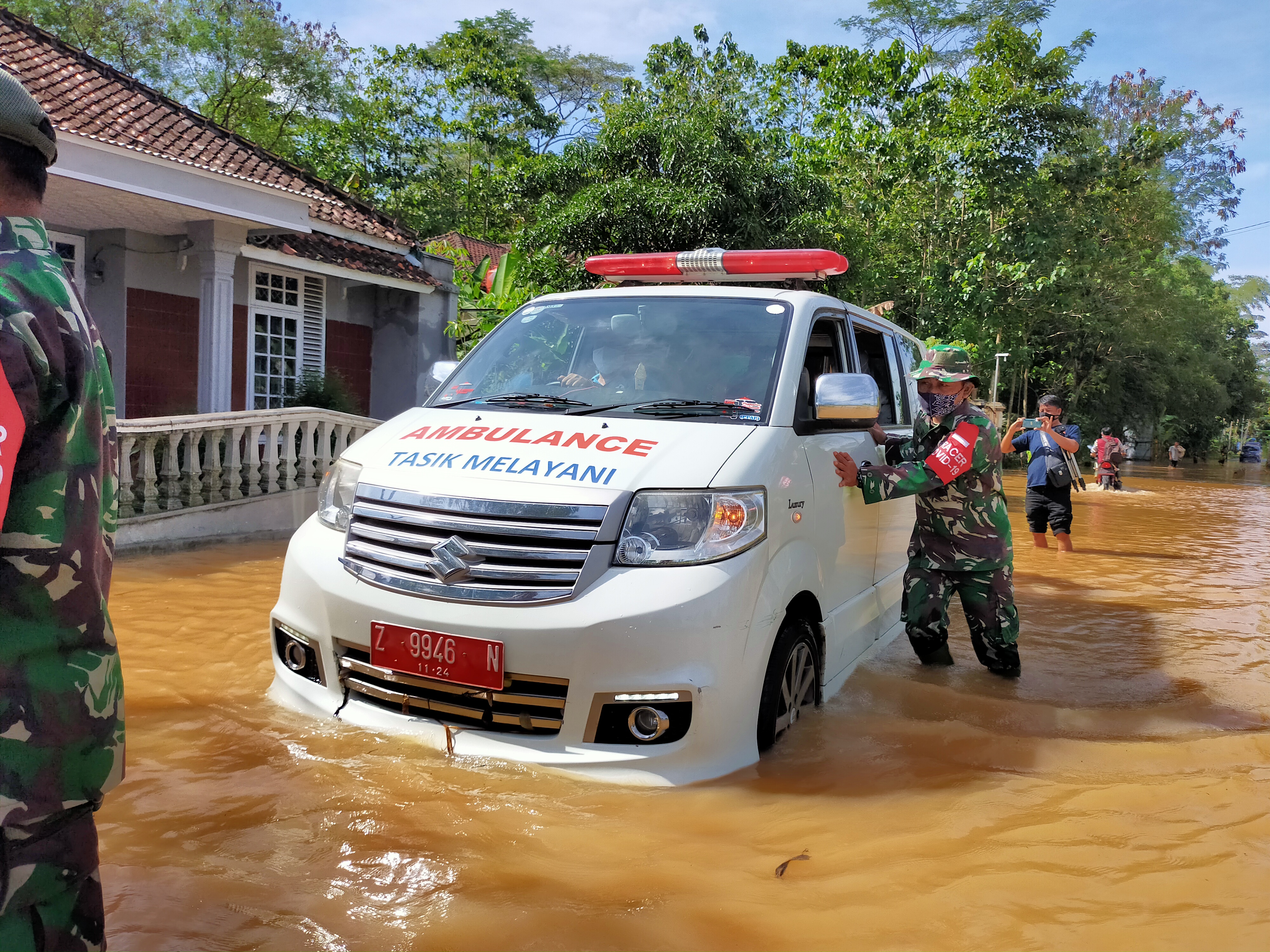 Anggota TNI mendorong ambulans puskesmas yang mogok karena terjebak banjir di Kecamatan Sukaresik, Kabupaten Tasikmalaya, Kamis (25/3/2021).