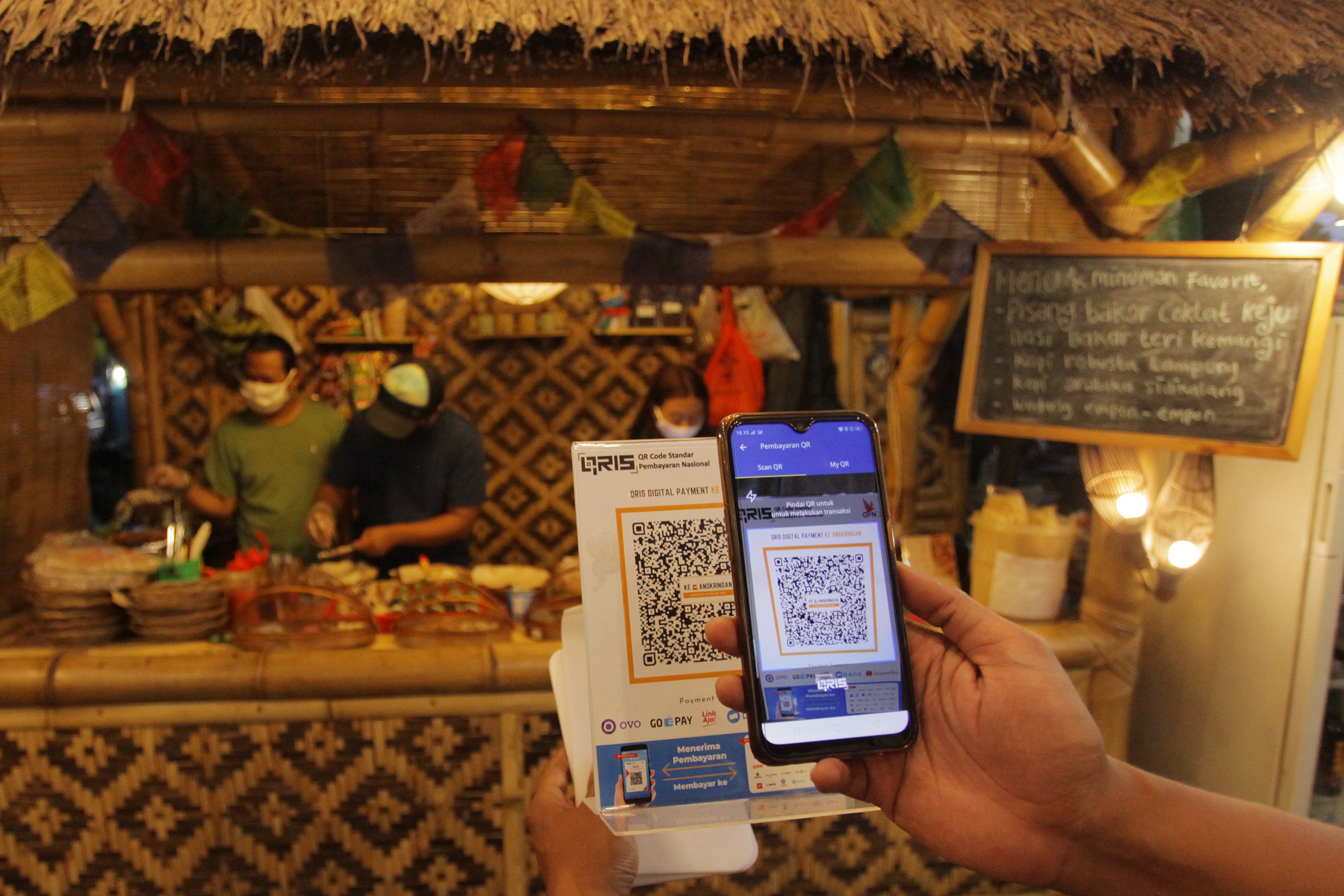 Konsumen membayar pesanannya melalui kode Quick Response Indonesia Standard (QRIS) di gerai Ke-Angkringan di Jalan Ampera Raya, Jakarta.