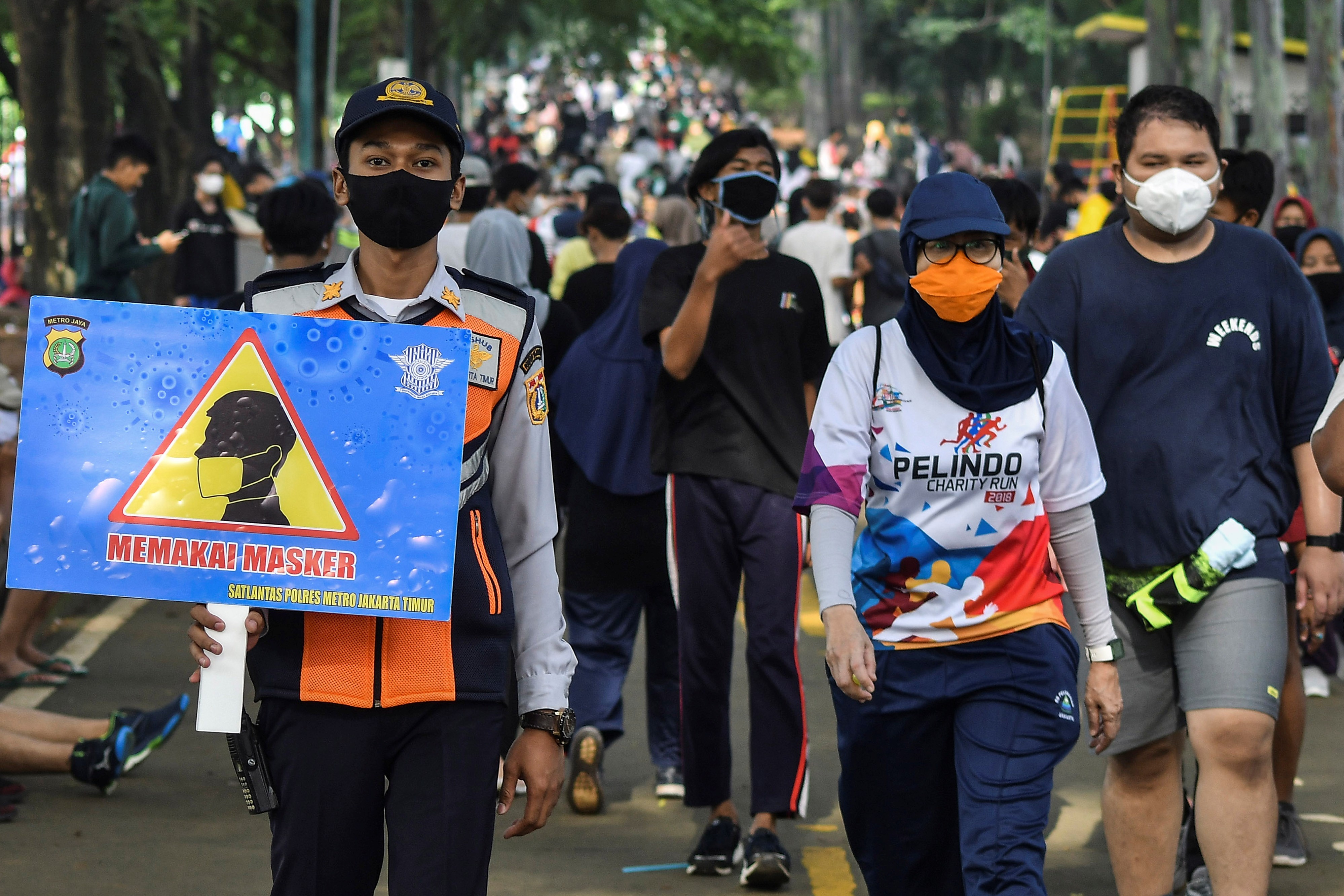 Petugas Dinas Perhubungan menyosialisasikan penggunaan masker kepada warga yang berolahraga di kawasan Kanal Banjir Timur, Jakarta.
