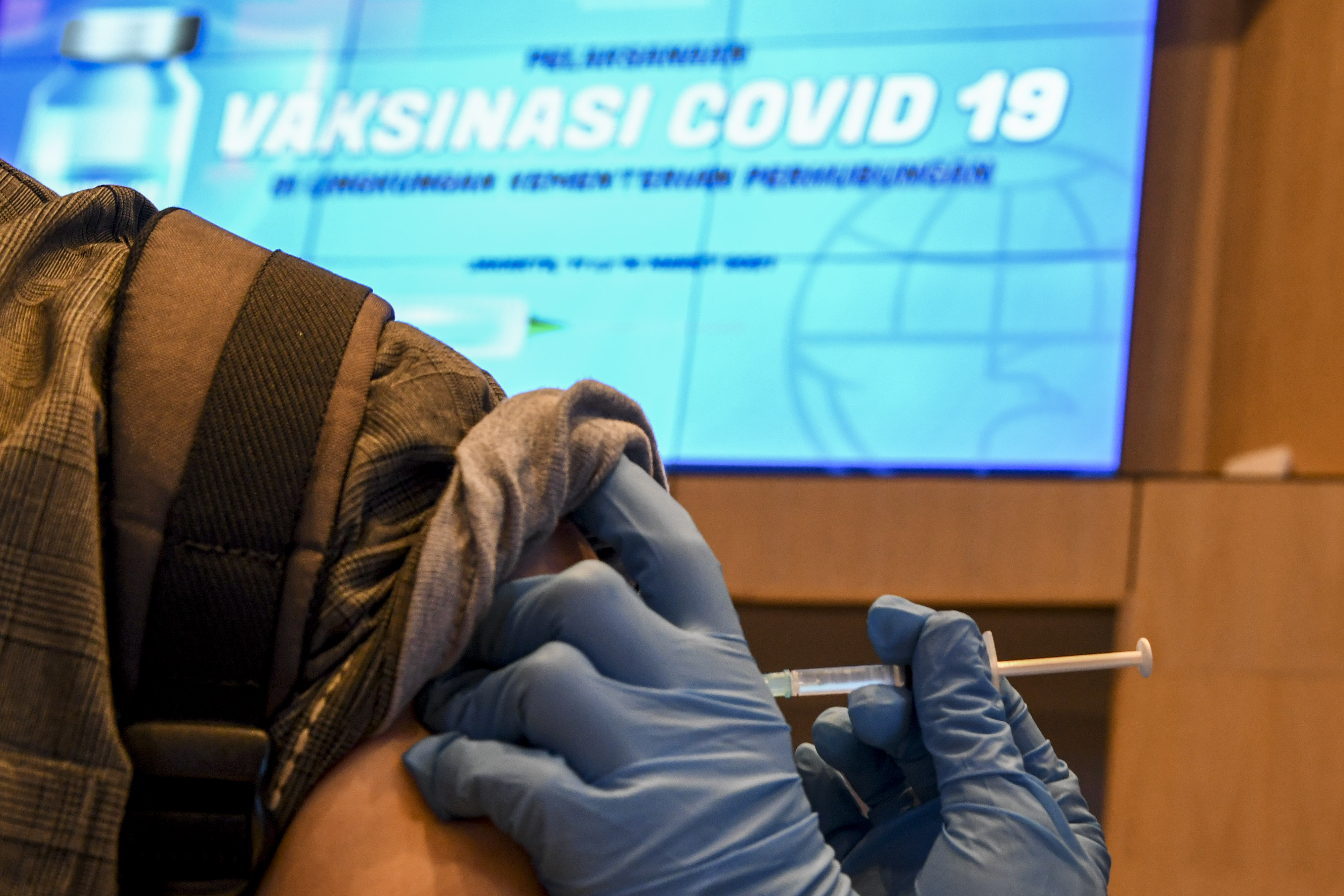 Ilustrasi vaksinator menyuntikkan vaksin covid-19 kepada seorang warga.