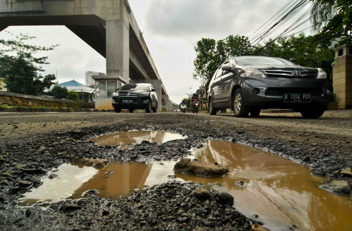 Sejumlah kendaraan memperlambat laju kendaraannya untuk menghindari lubang di kawasan Kelapa Gading, Jakarta Utara.