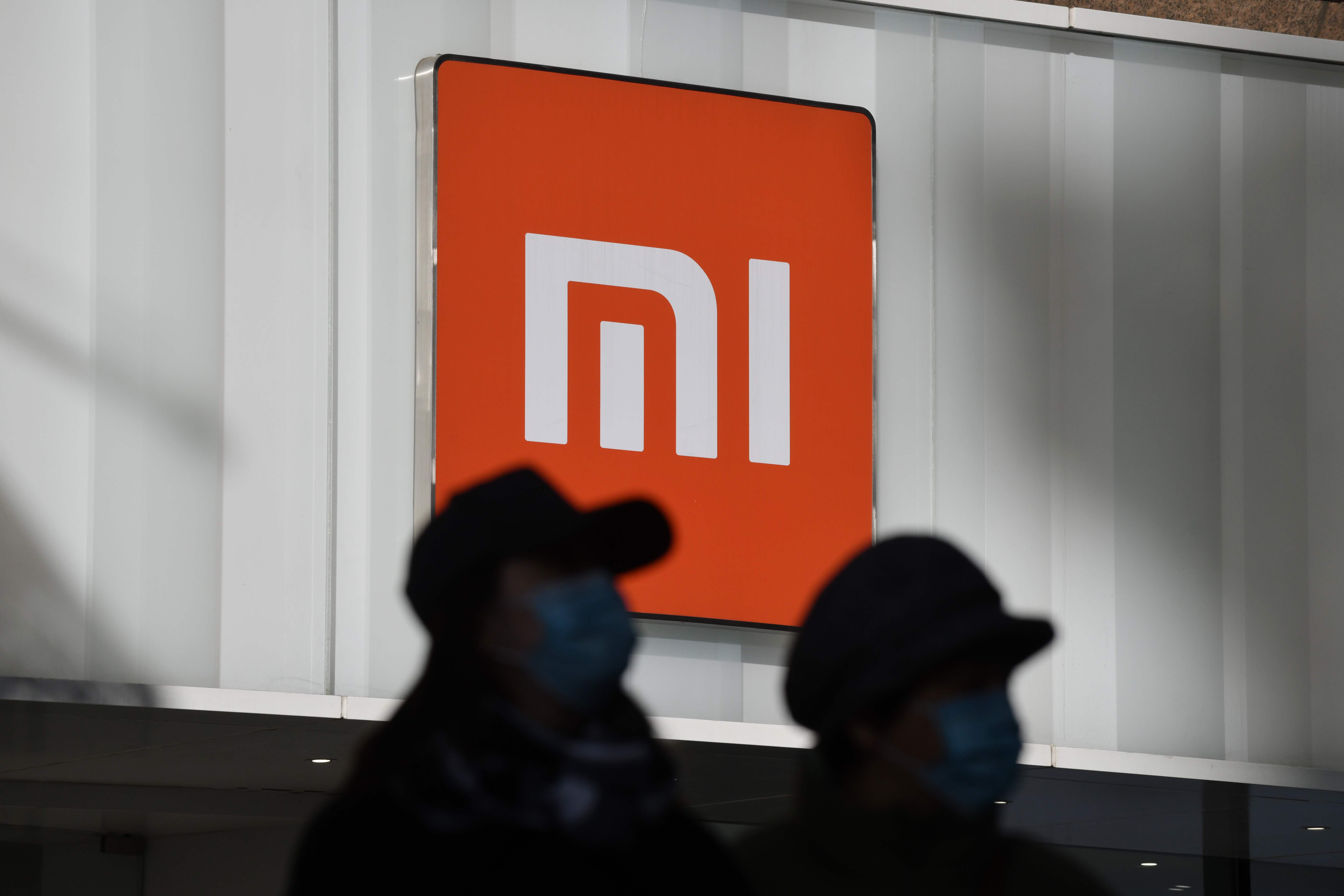 Warga berjalan di depan toko Xiaomi di Beijing, Tiongkok, Januari 2021. Kini Xiaomi akan investasi pengembangan mobil listrik pintar. 
