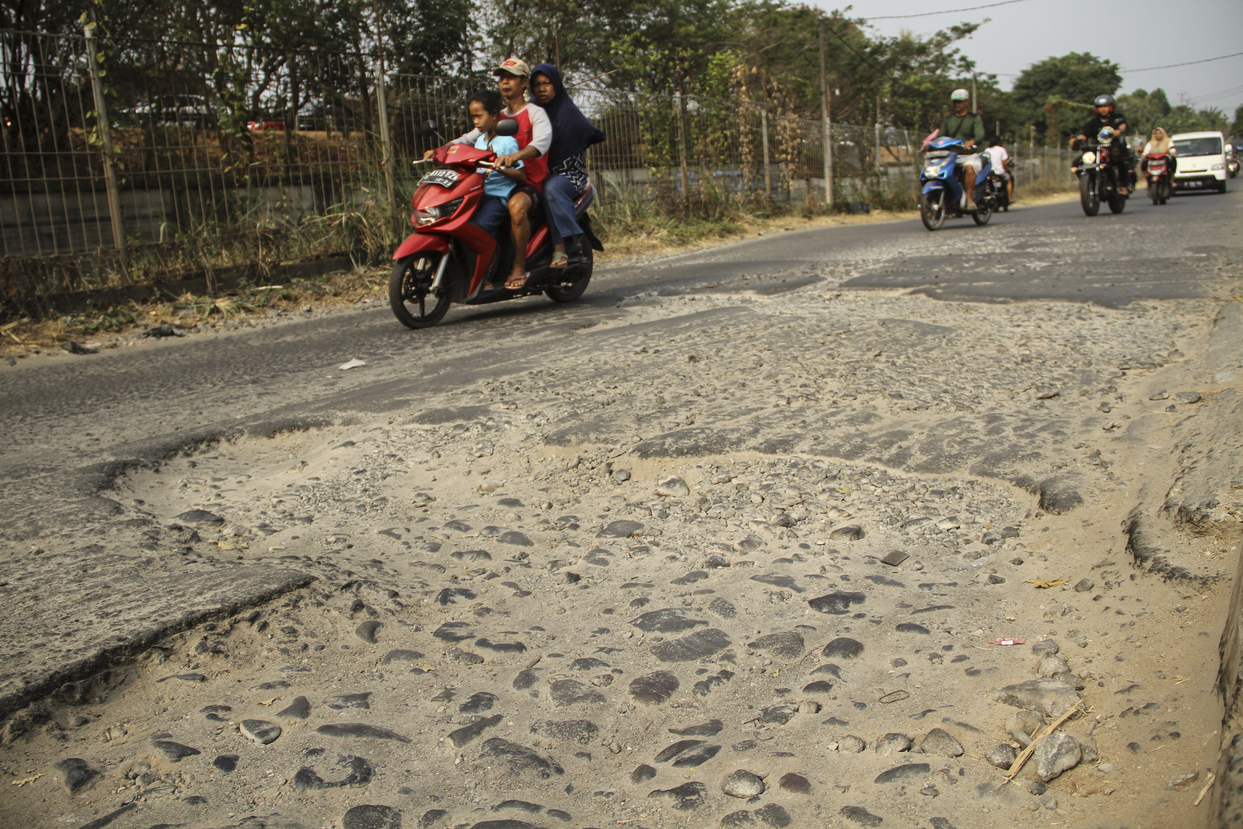Sejumlah pengendara menghindari jalan yang rusak di Jalan Gas Alam, Depok, Jawa Barat, Minggu (25/8/2019)