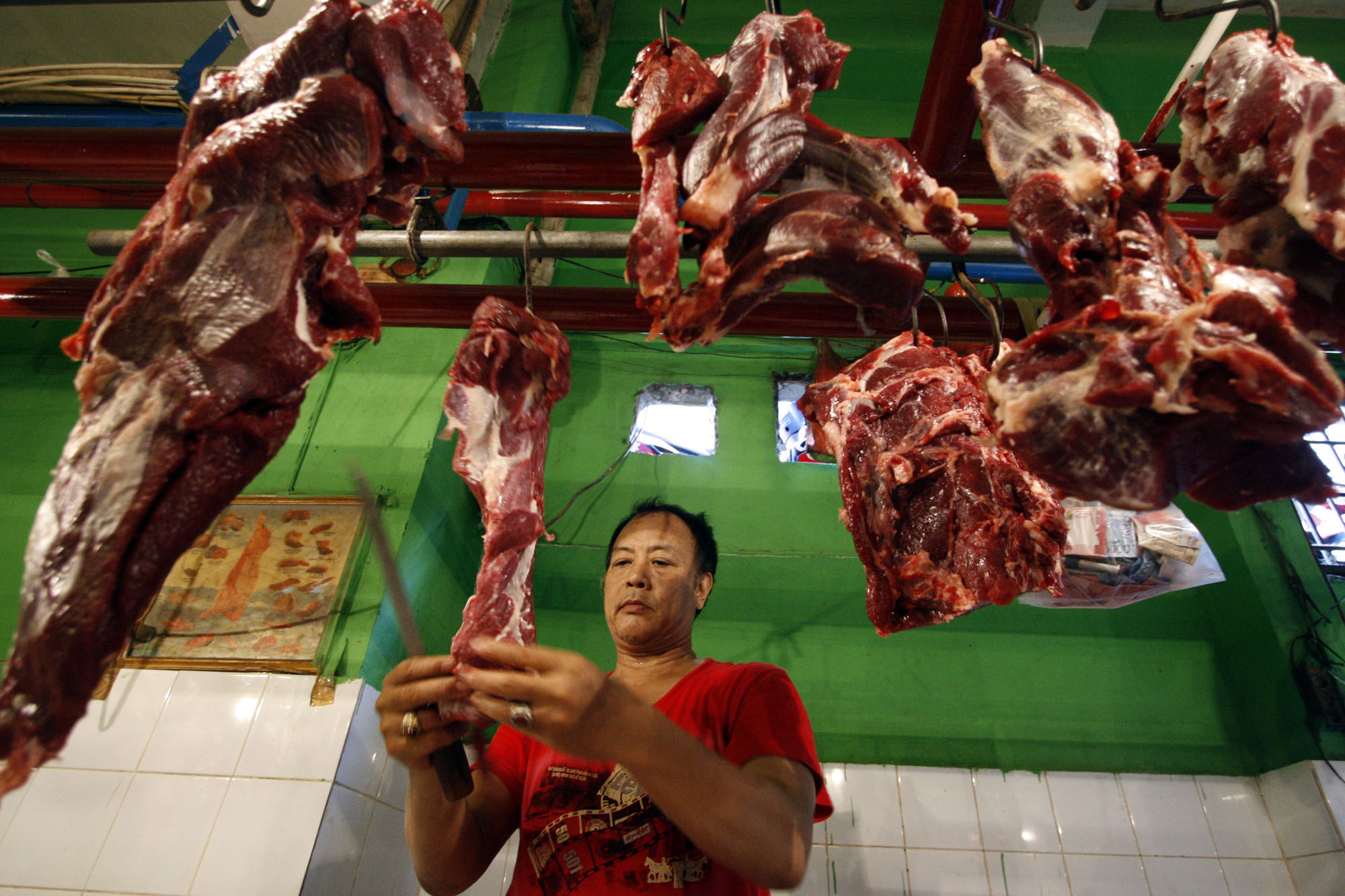 Penjual memotong daging dagangannya di Pasar Jatinegara, Jakarta Timur