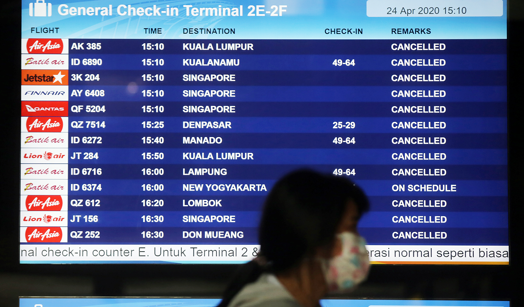 Calon penumpang melintas di depan papan pengumuman elektronik jadwal penerbangan di Bandara Soekarno Hatta, Tangerang pada 2020.