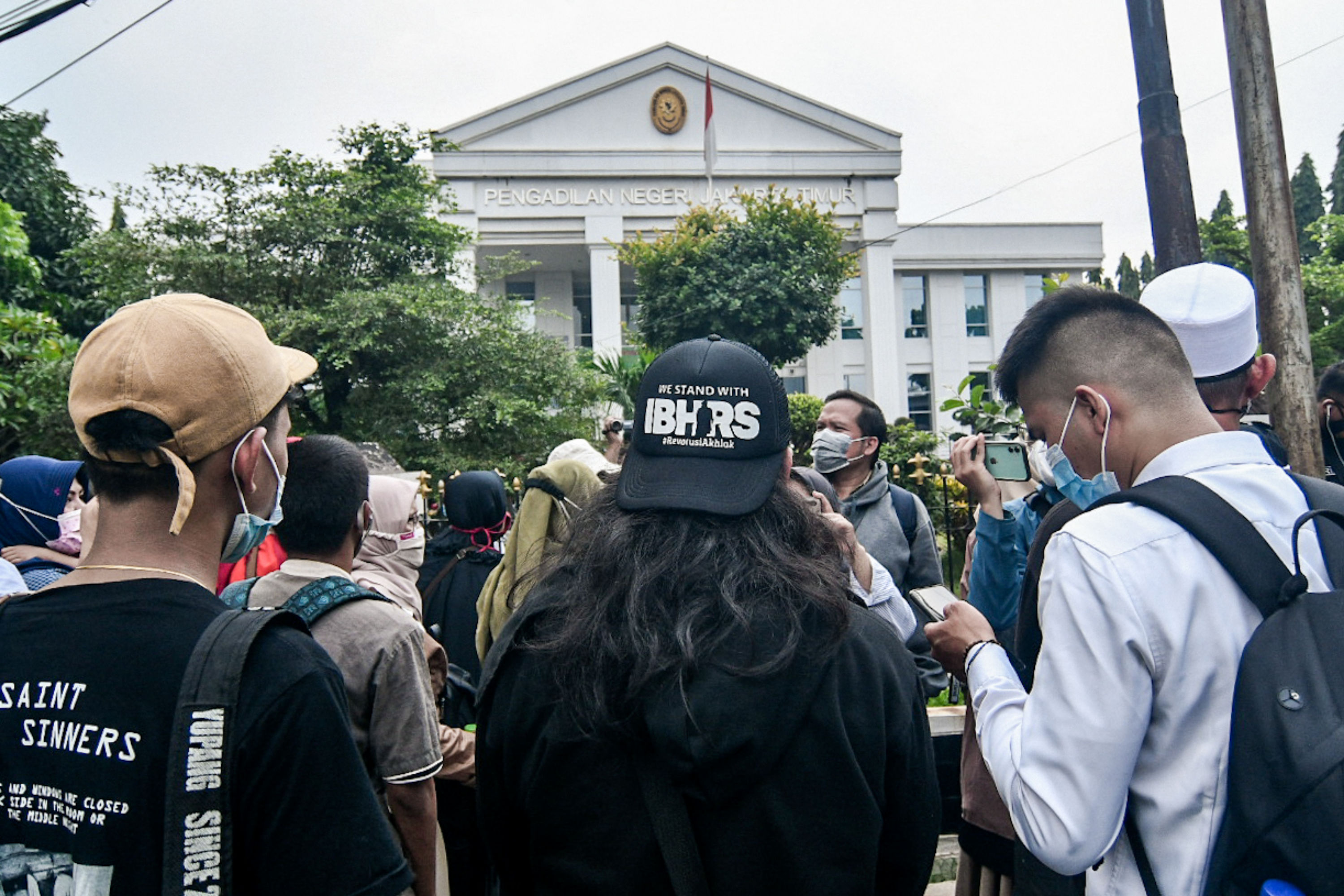 Massa berkumpul saat berlangsungnya sidang perdana kasus dengan terdakwa Rizieq Shihab di Pengadilan Negeri Jakarta Timur, Selasa (16/3).