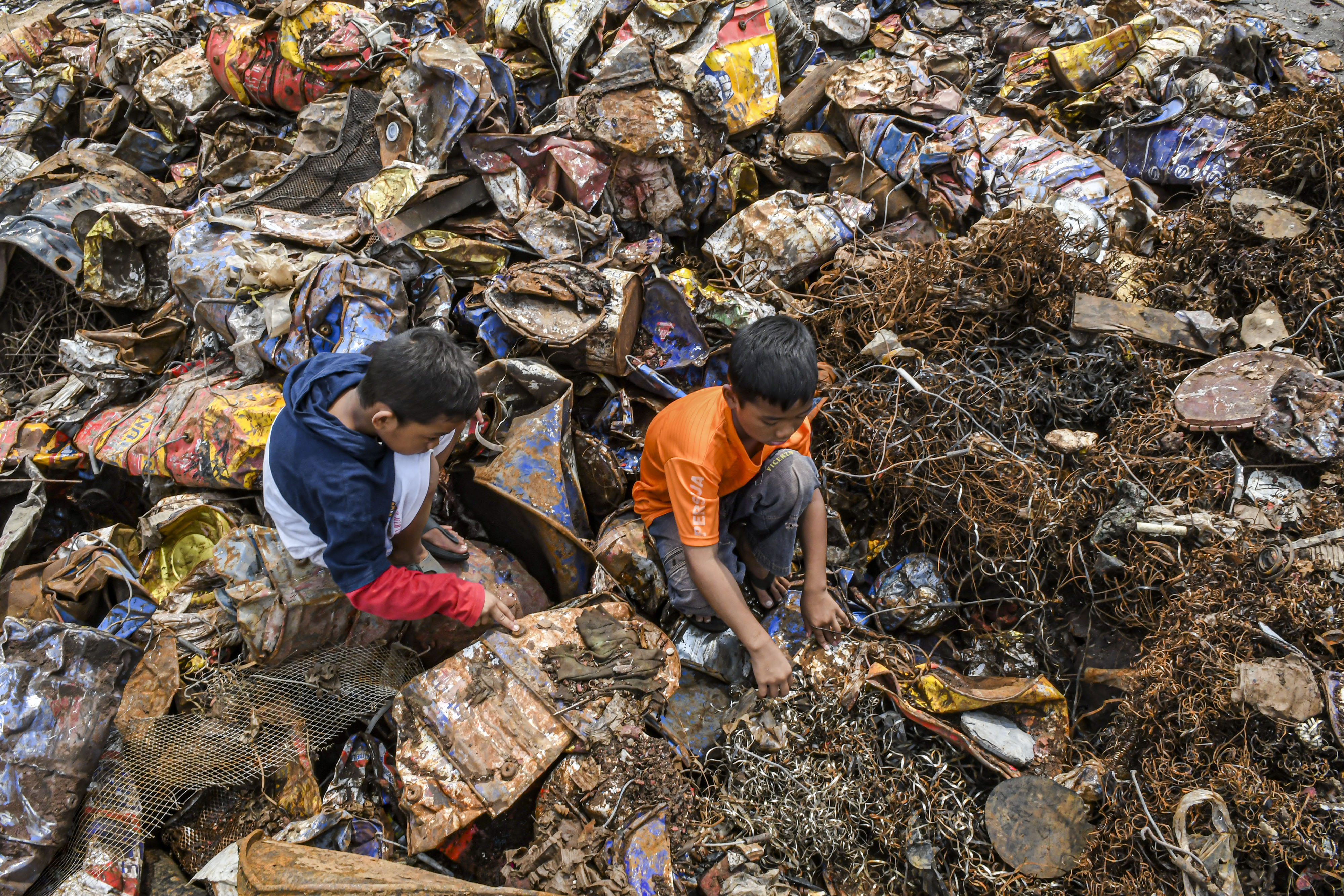 Anak-anak mencari sisa besi bekas di tumpukan limbah Bahan Beracun dan Berbahaya (B3) di Jakarta, Jumat (27/12/2019)