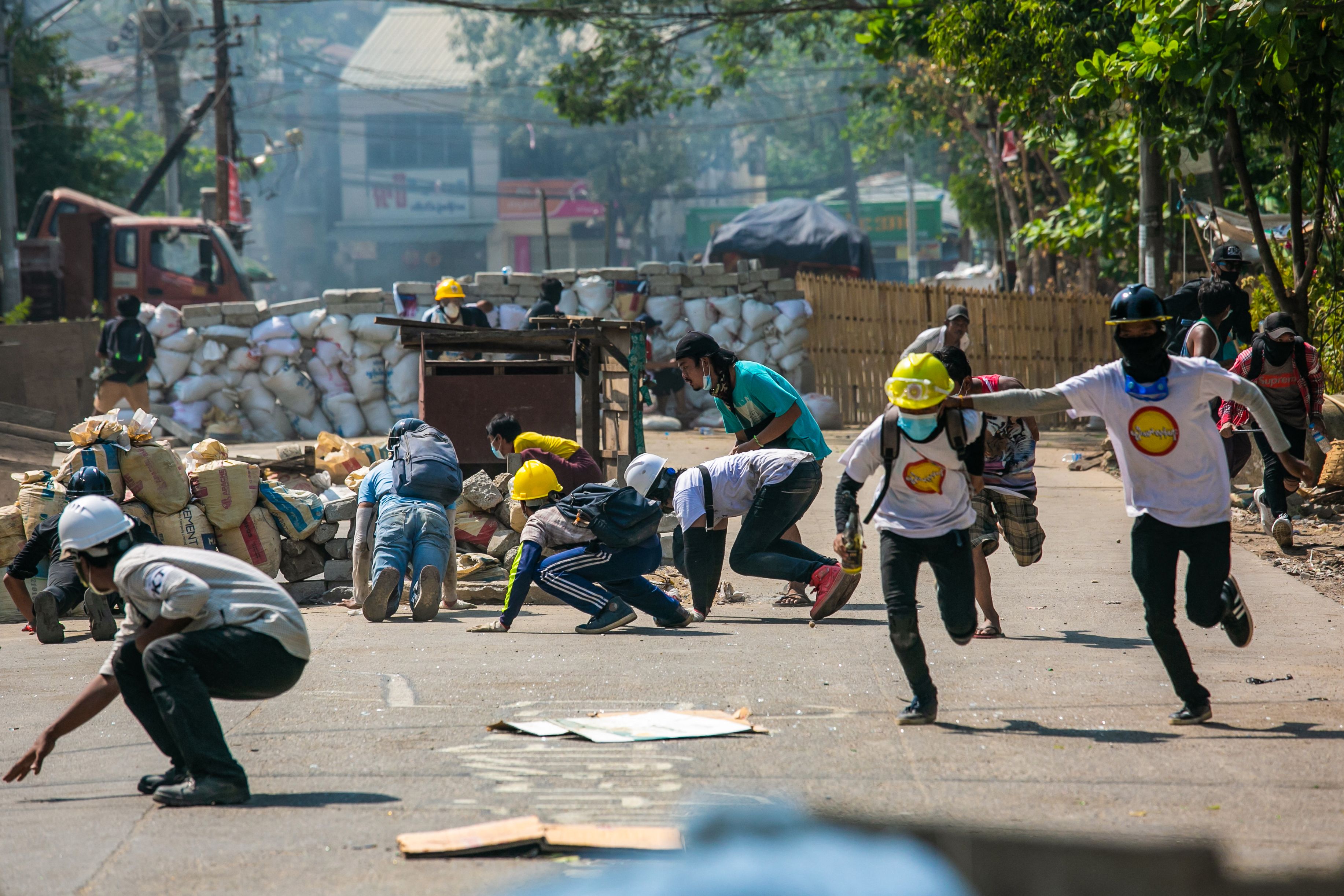 Demonstran berlindung saat terlibat bentrok dengan pasukan keamanan di Yangon, Myanmar.