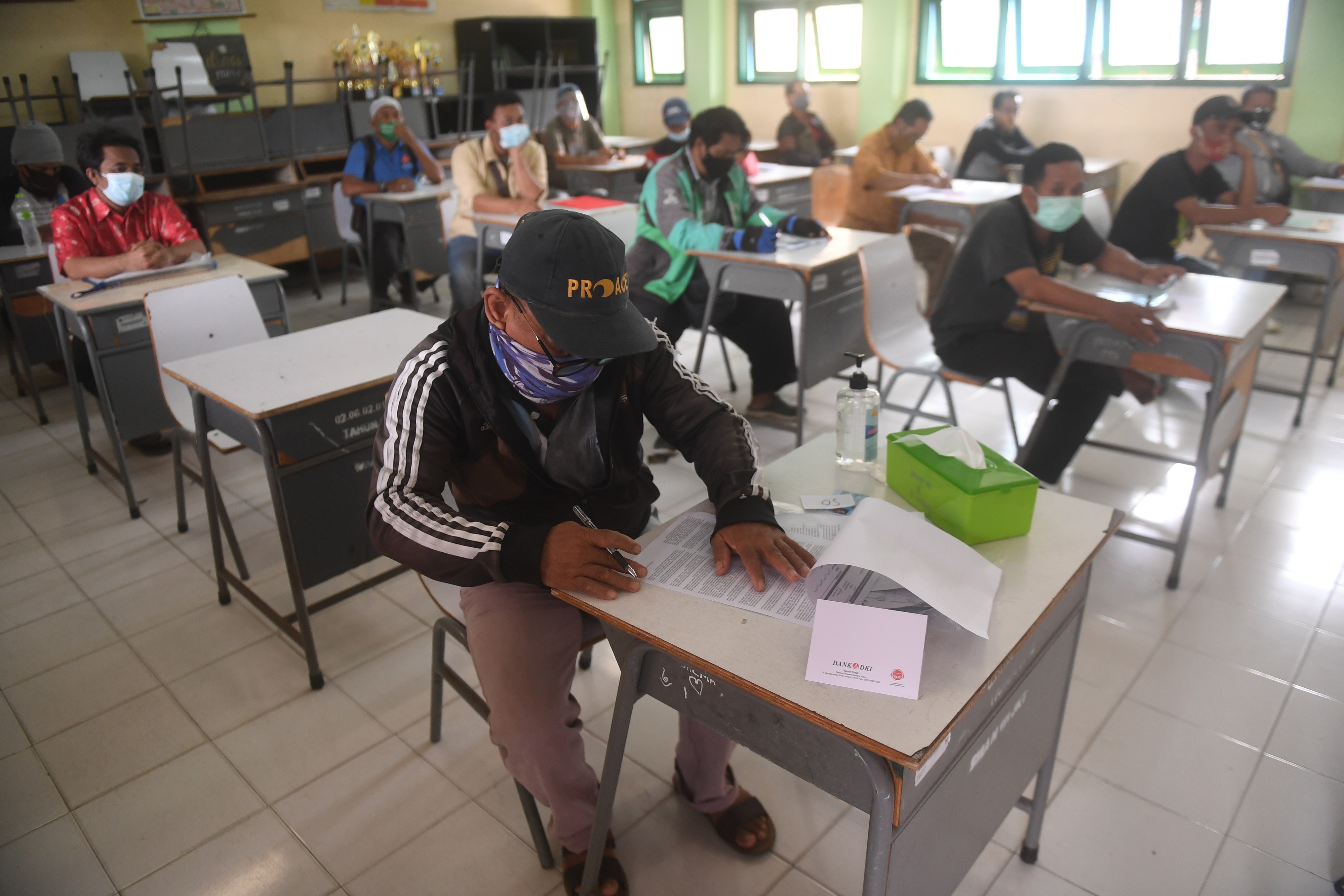 Warga mengisi dokumen persyaratan saat mengambil bantuan sosial tunai di SMAN 111, Jakarta, beberapa waktu lalu.