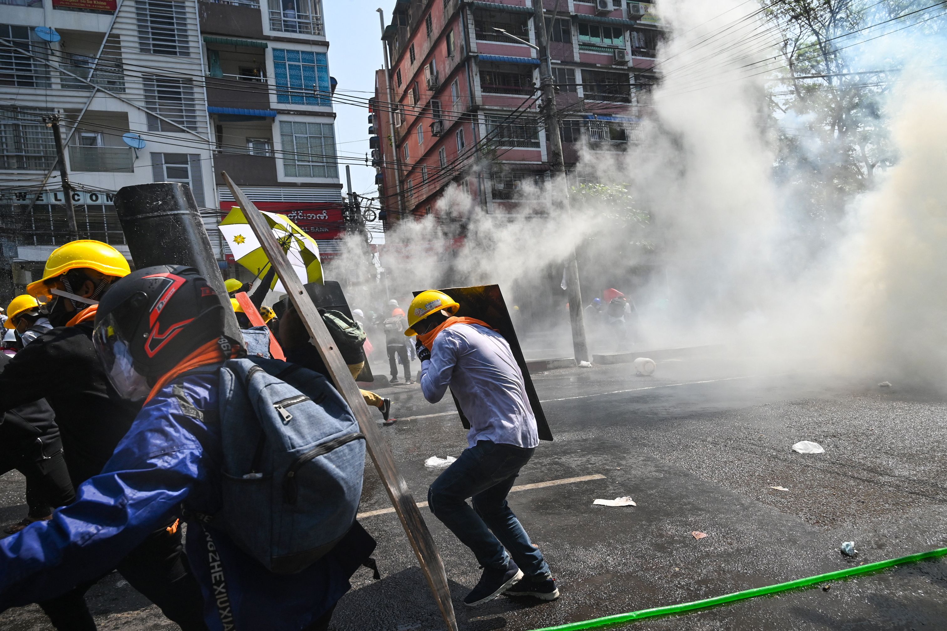 Sejumlah demonstran di Yangon, Myanmar, berusaha menghindar dari tembakan gas air mata.