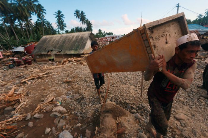 Warga korban banjir menyelamatkan sisa perabot yang terdampak banjir bandang di Gorontalo.  