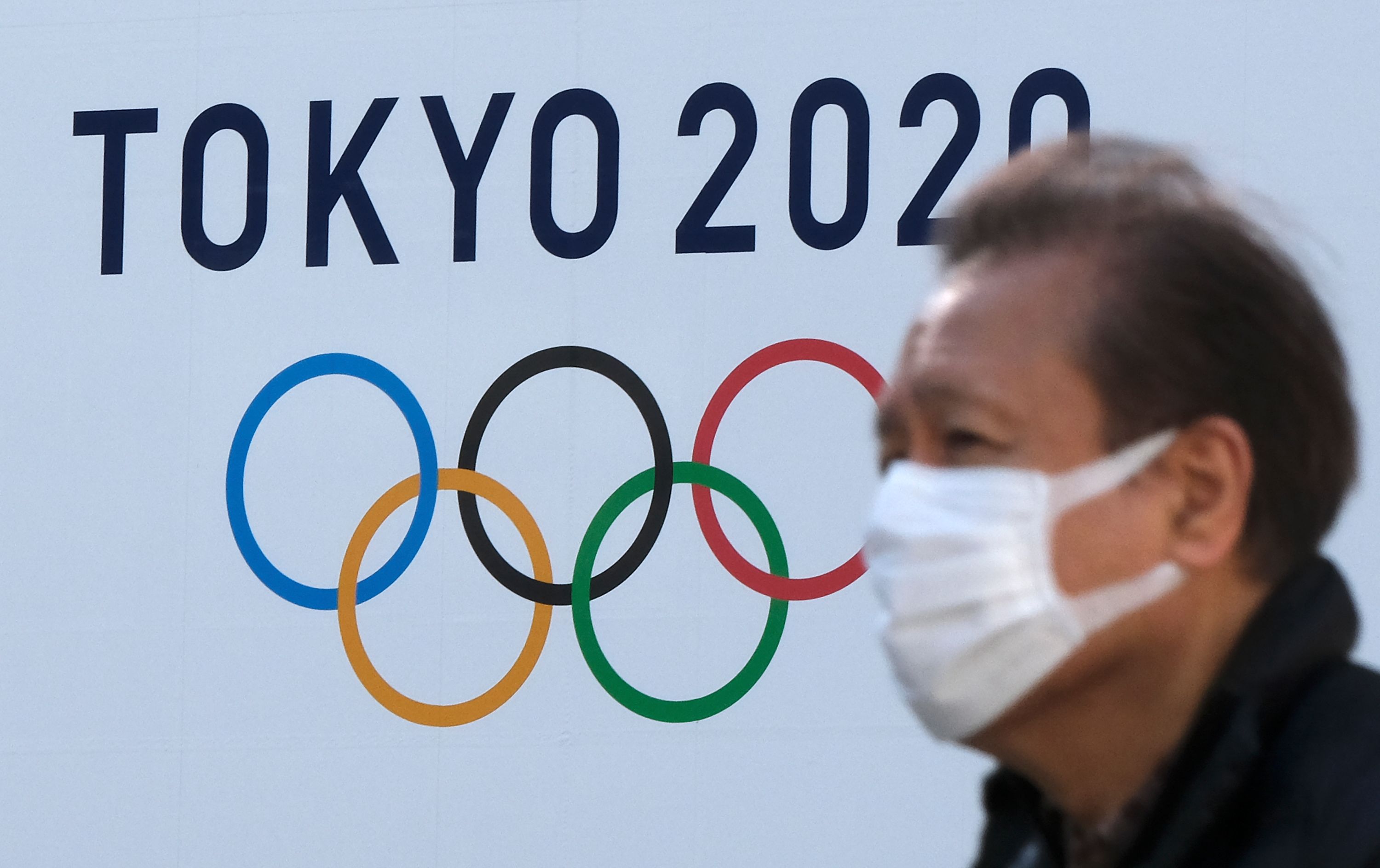 Seorang pria berjalan di depan logo Olimpiade Tokyo 2020 di Tokyo, Jepang.