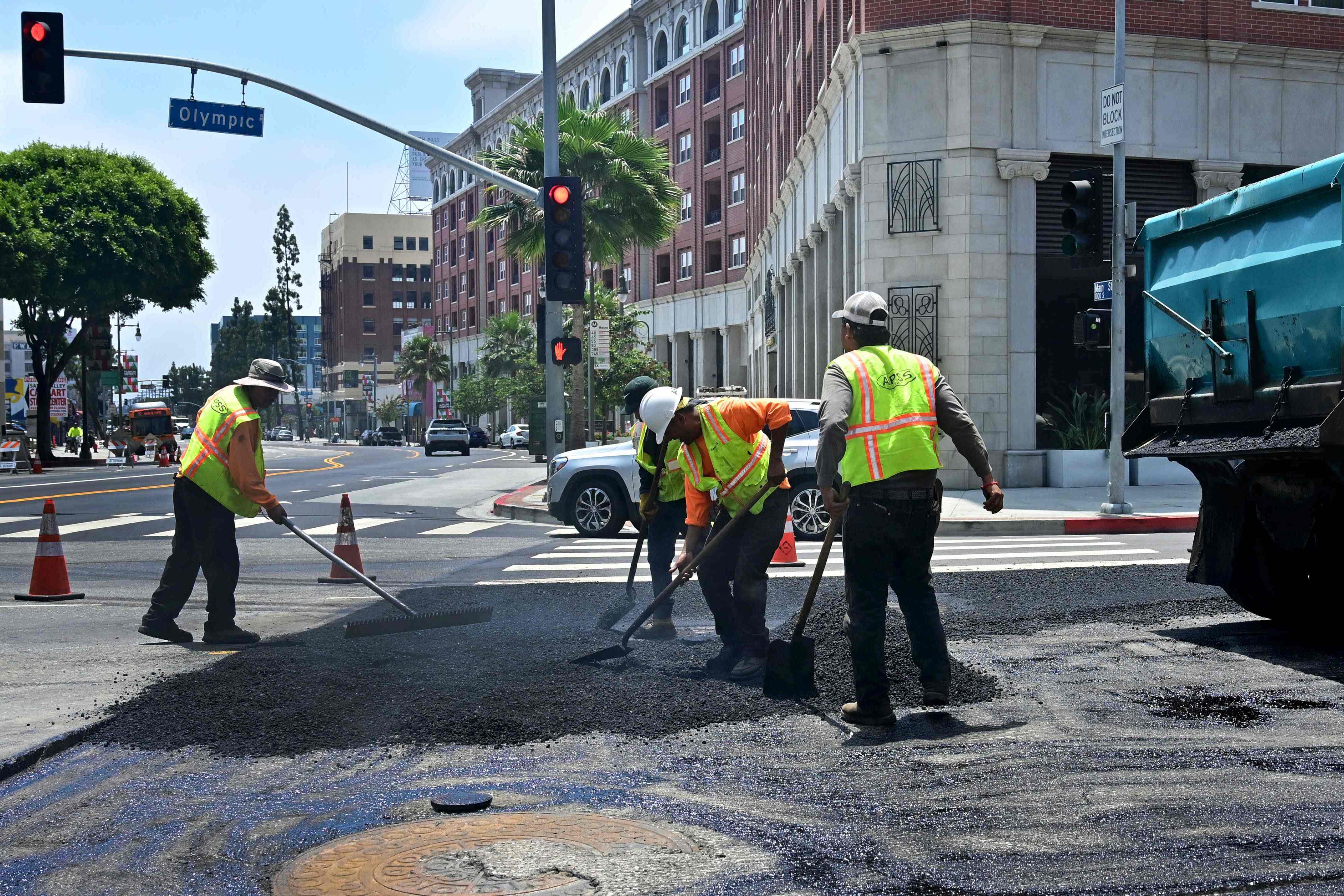 Pekerja muncul kembali di jalan dengan menuangkan lapisan aspal baru di Los Angeles, California, beberapa waktu lalu.