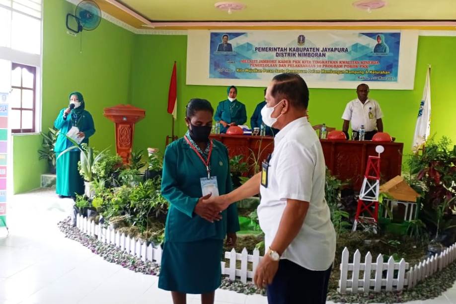 Kadistrik Nimboran, Marsuki Ambo menyematkan kartu tanda peserta kepada salah satu perwakilan peserta Jambore Kader PKK Distrik Nimboran.