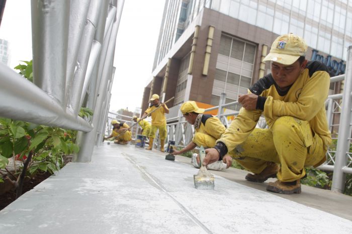 Petugas Dinas Bina Marga Pemprov DKI Jakarta melakukan pengecatan Jembatan Penyeberangan Orang (JPO) tanpa atap.