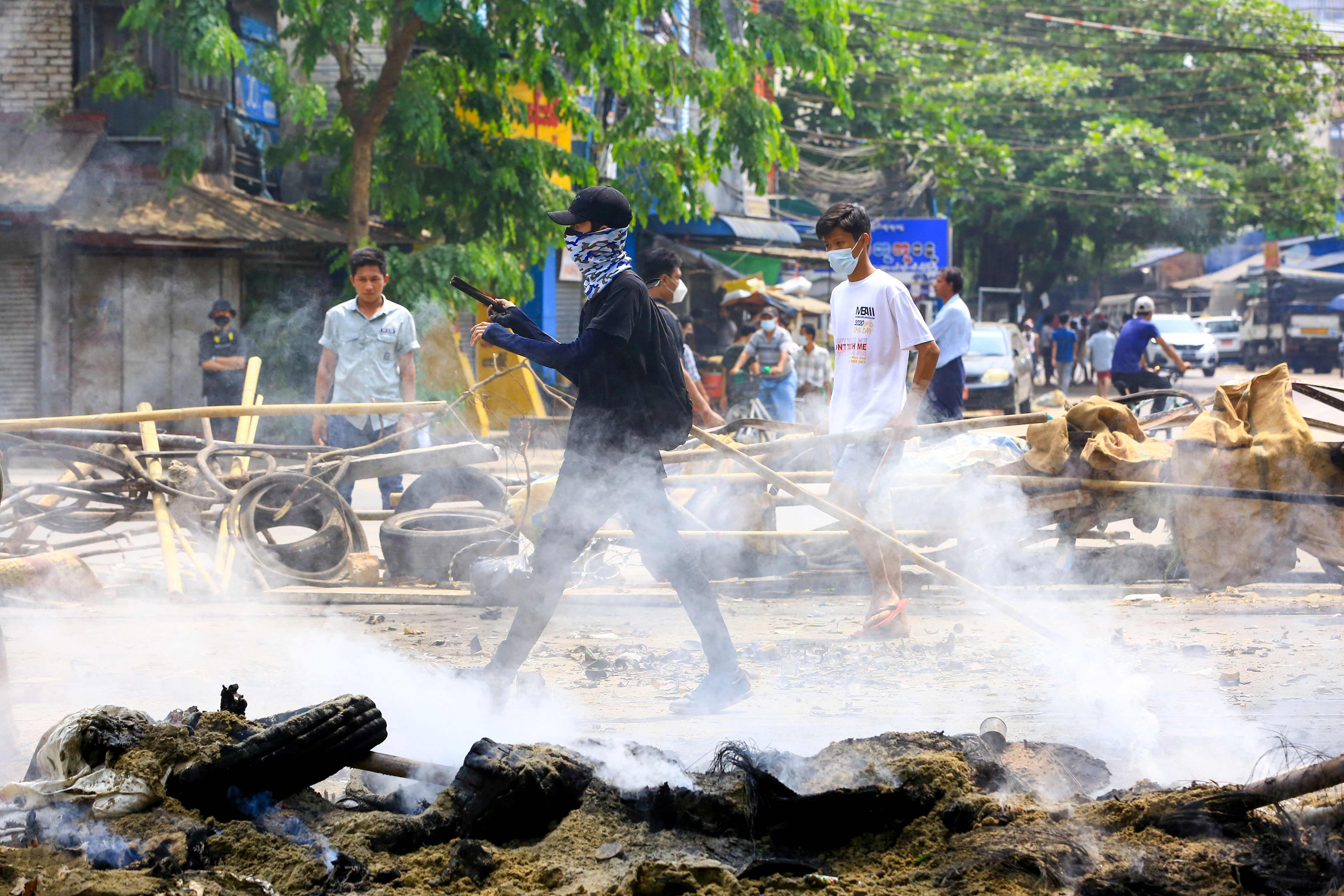 Demonstran berjalan di antara barikade yang dibangun dalam aksi demonstrasi di Yangon, Myanmar.